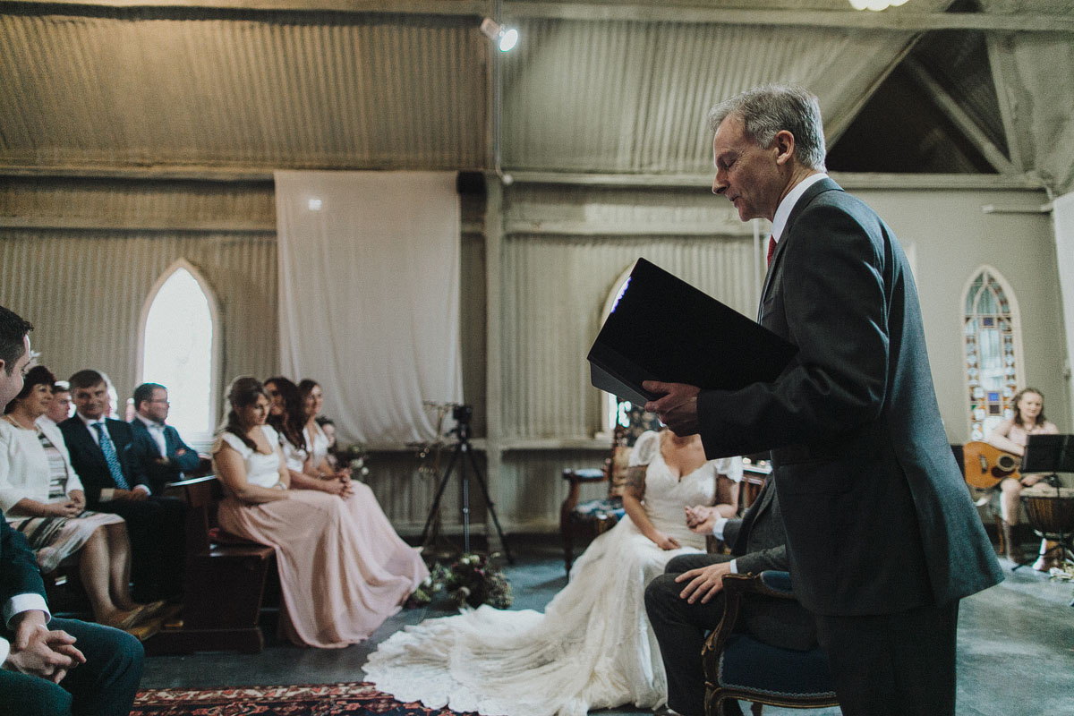 billy hutchinson humanist celebrant reading from script at wedding ceremony in a ceremony venue with guests watching