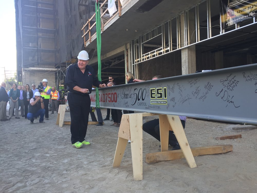 Developer Brian Obie signs the final beam before it is hoisted into place