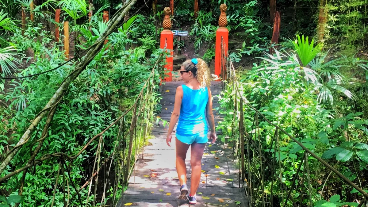 Guest walking across suspension bridge in botanical gardens with My Deztination.