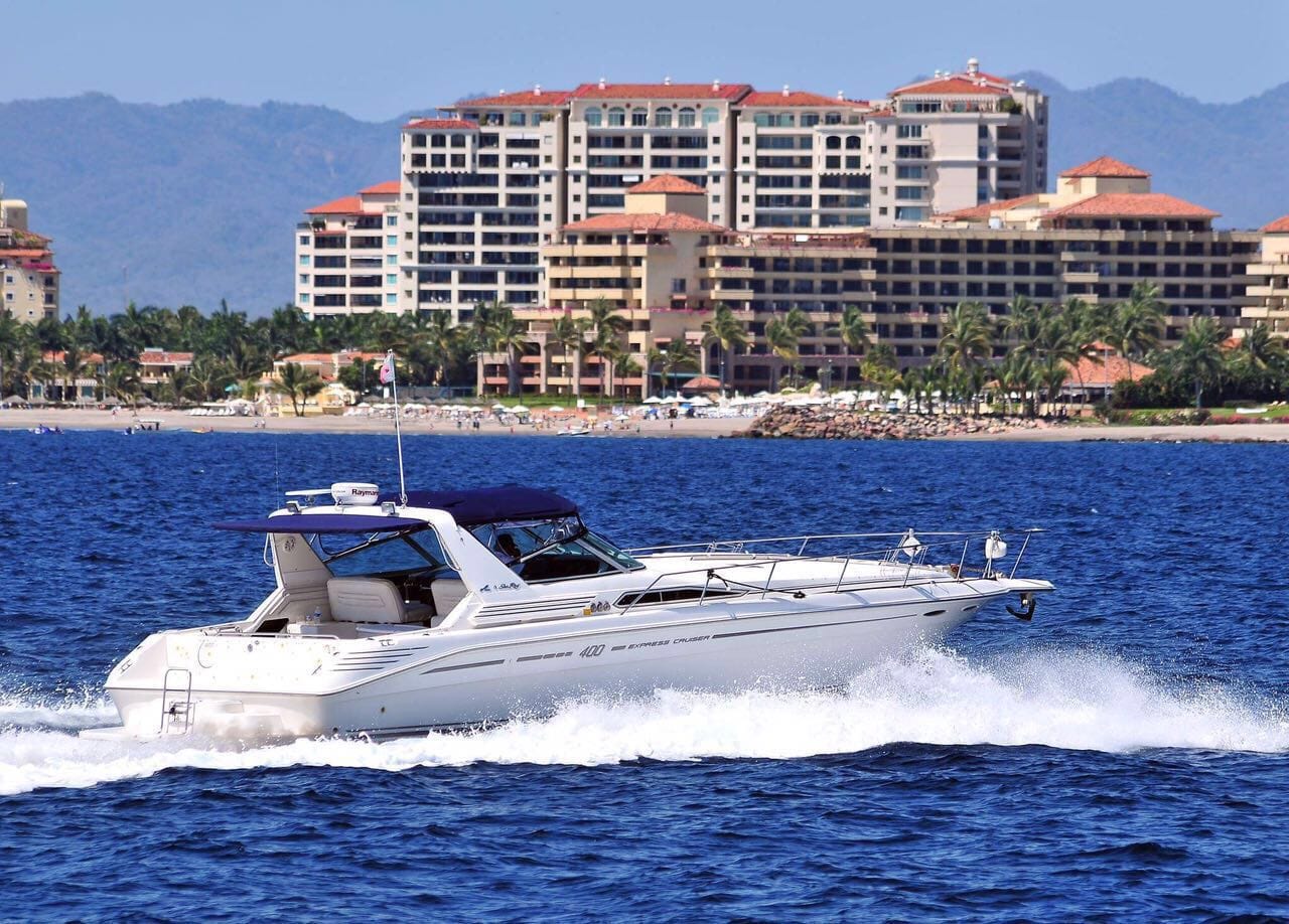 Yacht cruising fast with beaches and hotels in background, My Deztination.