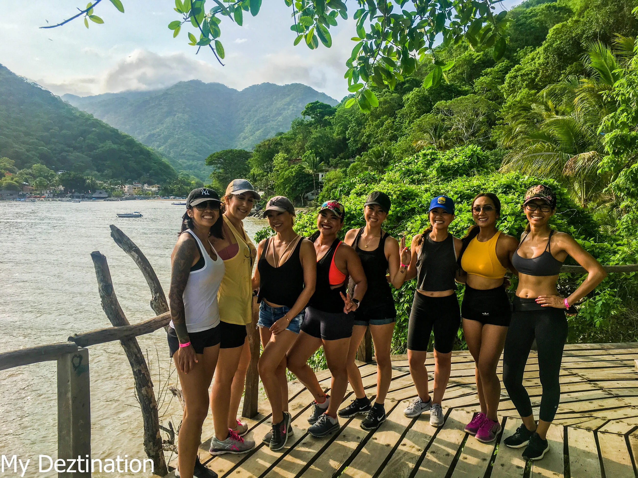Group of girls smiling along jungle trail with ocean view in Puerto Vallarta.