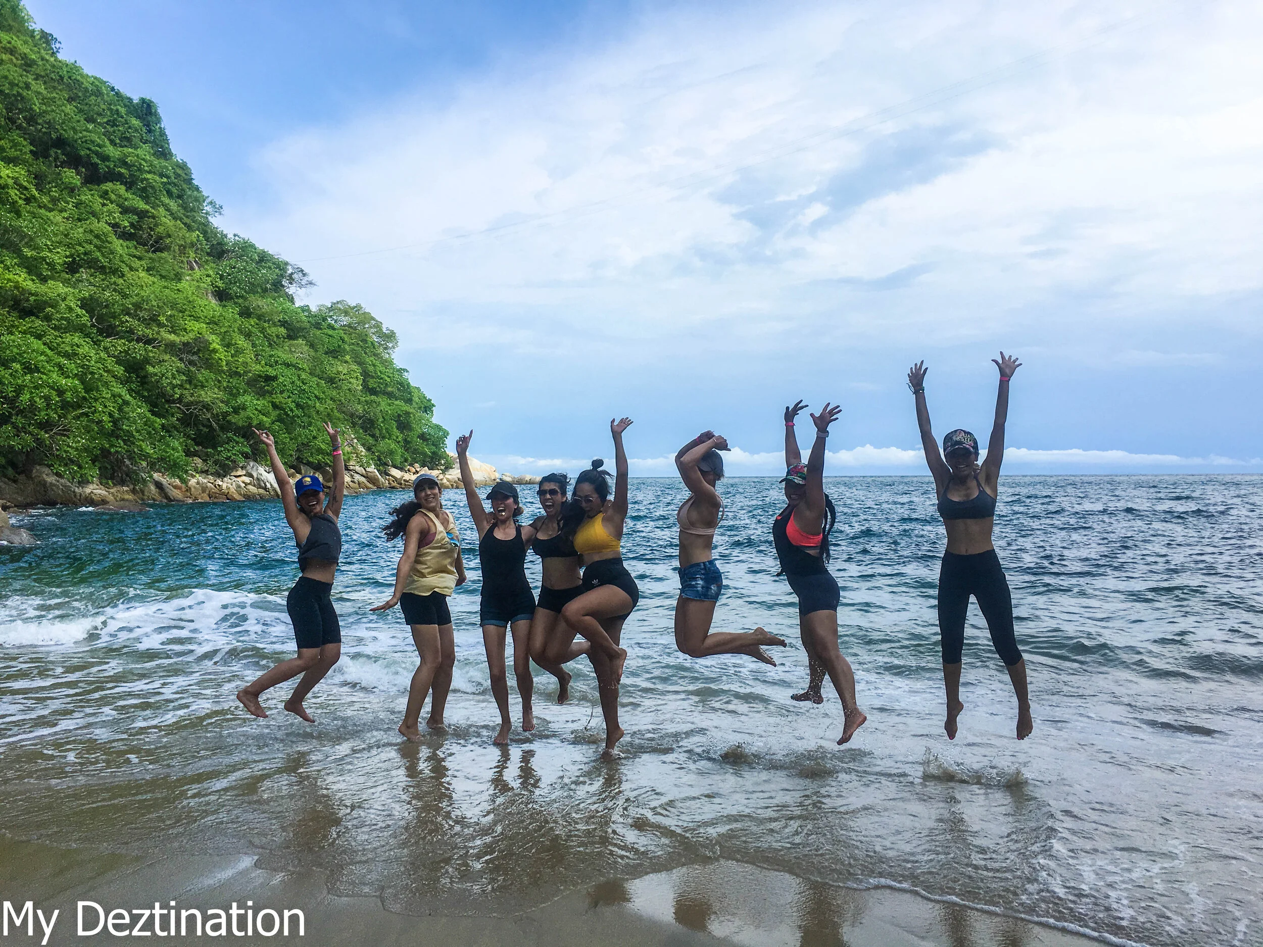Girls jumping and laughing on Playa Colomitos during My Deztination tour.