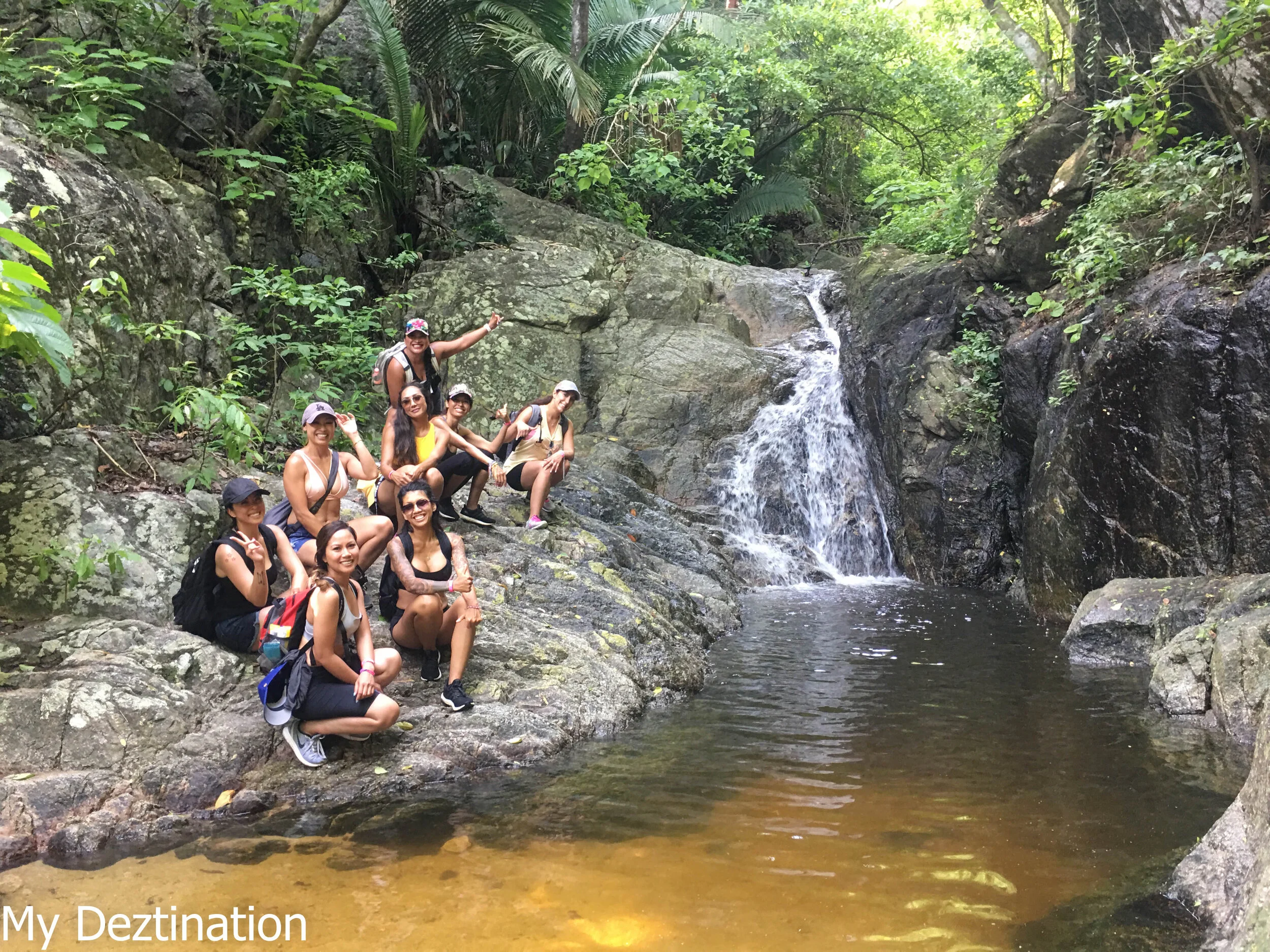 A group of hikers sits by a small seasonal waterfall along the Los Animas Jungle Coastline Trail—discover this hidden gem on My Deztination’s guided hiking adventure.