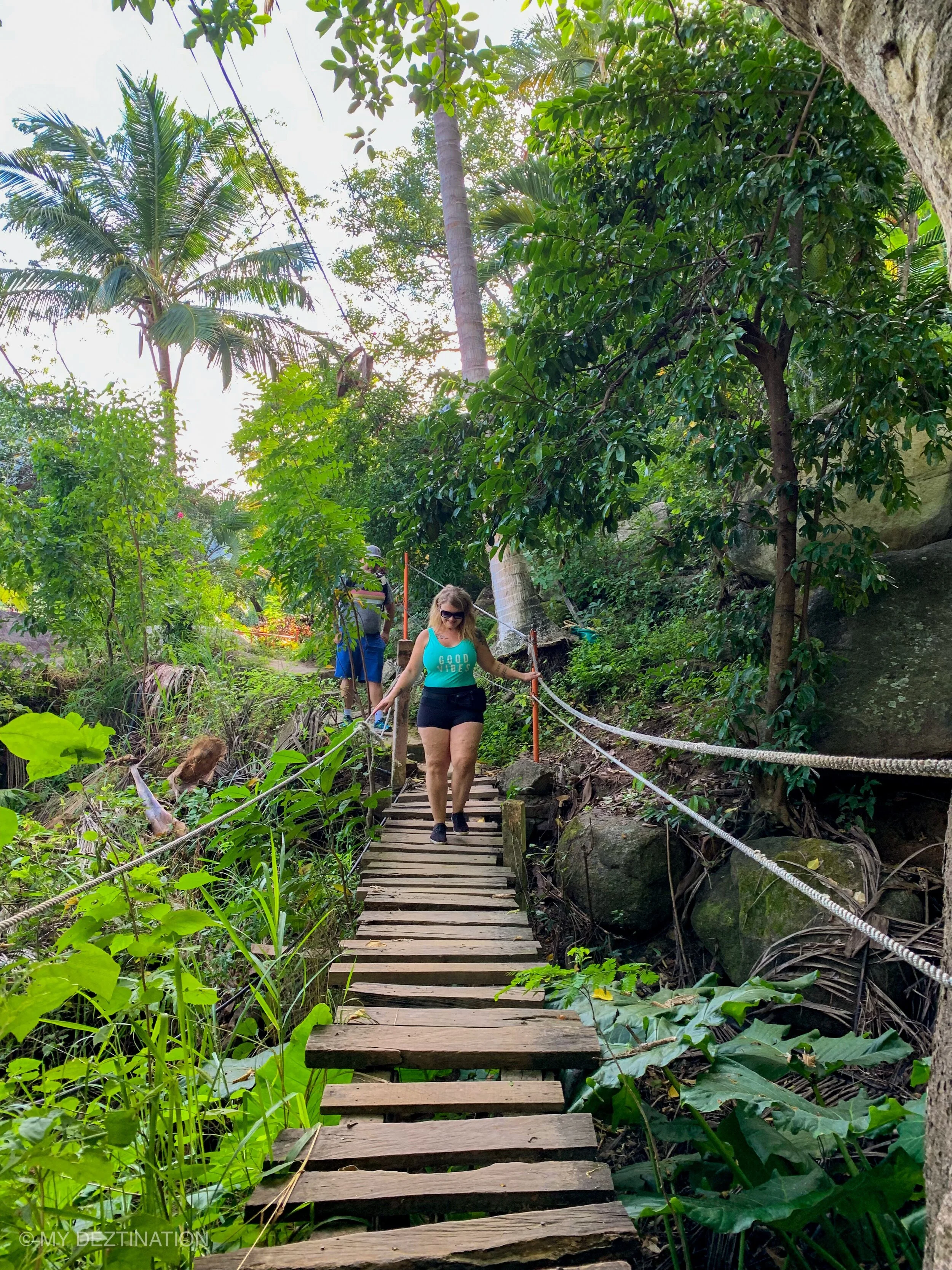 Guest crossing wooden bridge on coastal trail near Boca de Tomatlán during My Deztination tour.