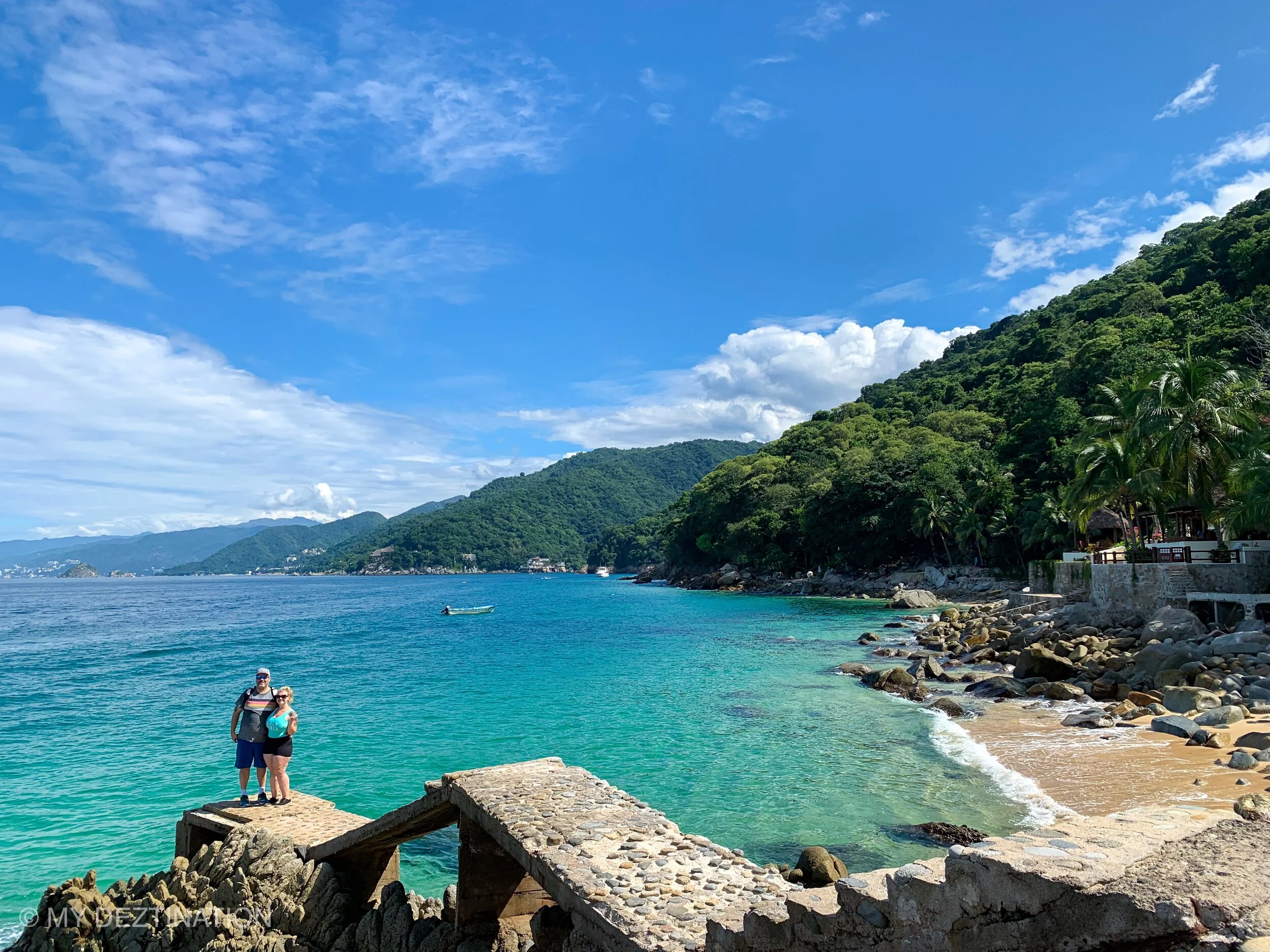 Couple posing with Los Arcos islands in background on coastal trail with My Deztination.