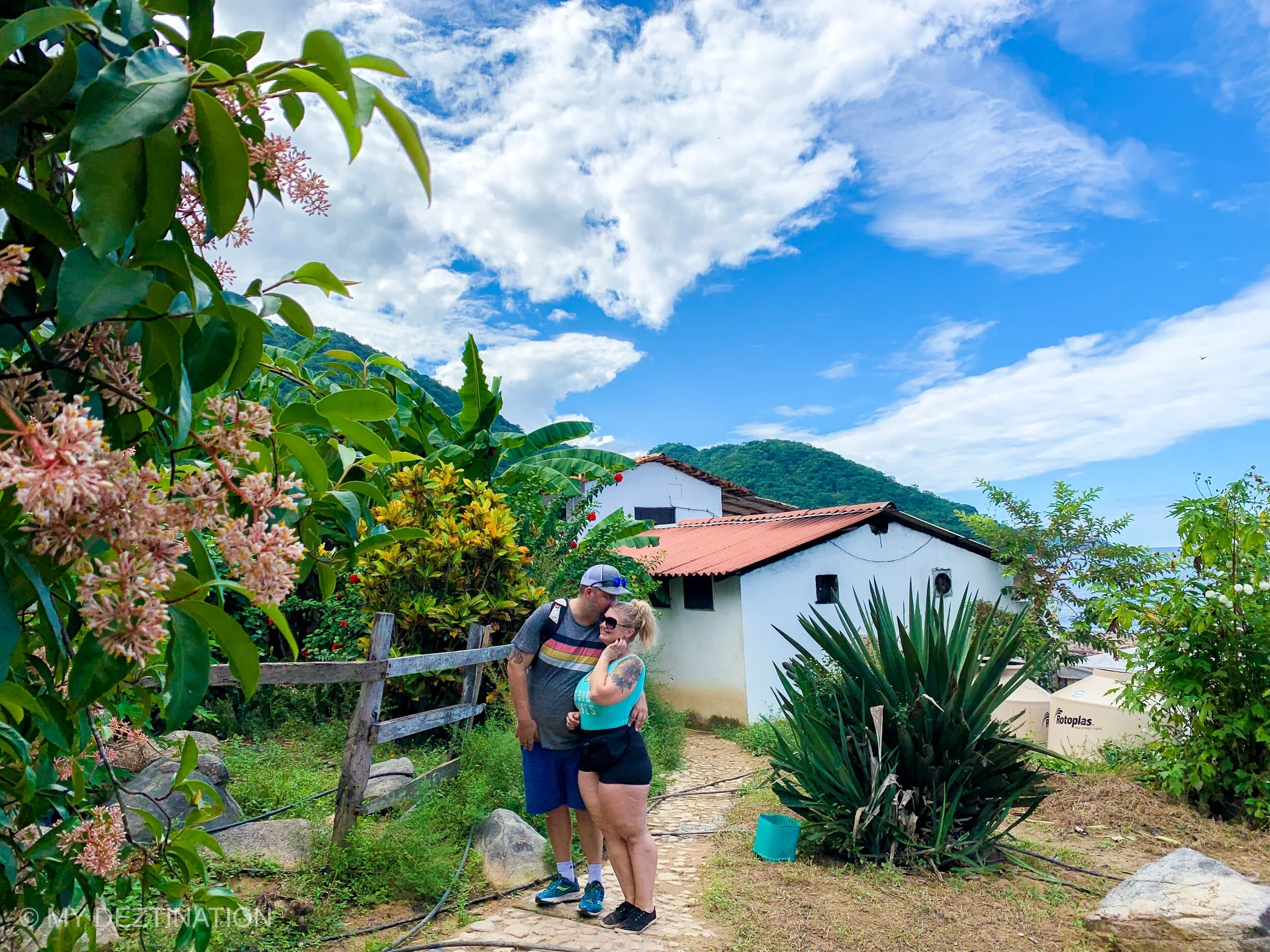 Couple in rustic village near Las Ánimas, smiling as he kisses her forehead on a tour with My Deztination