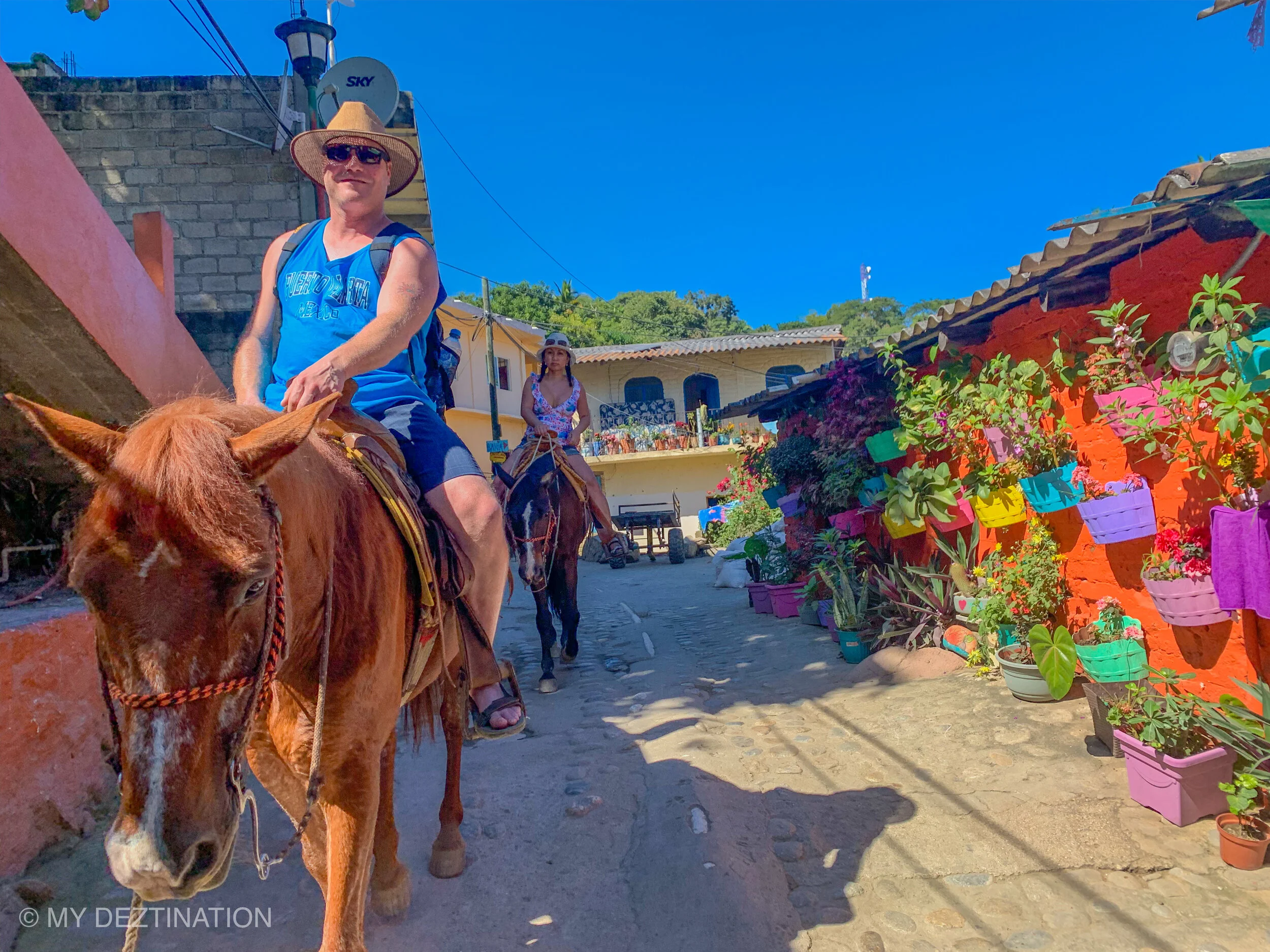 Couple riding horses through Yelapa village with My Deztination.