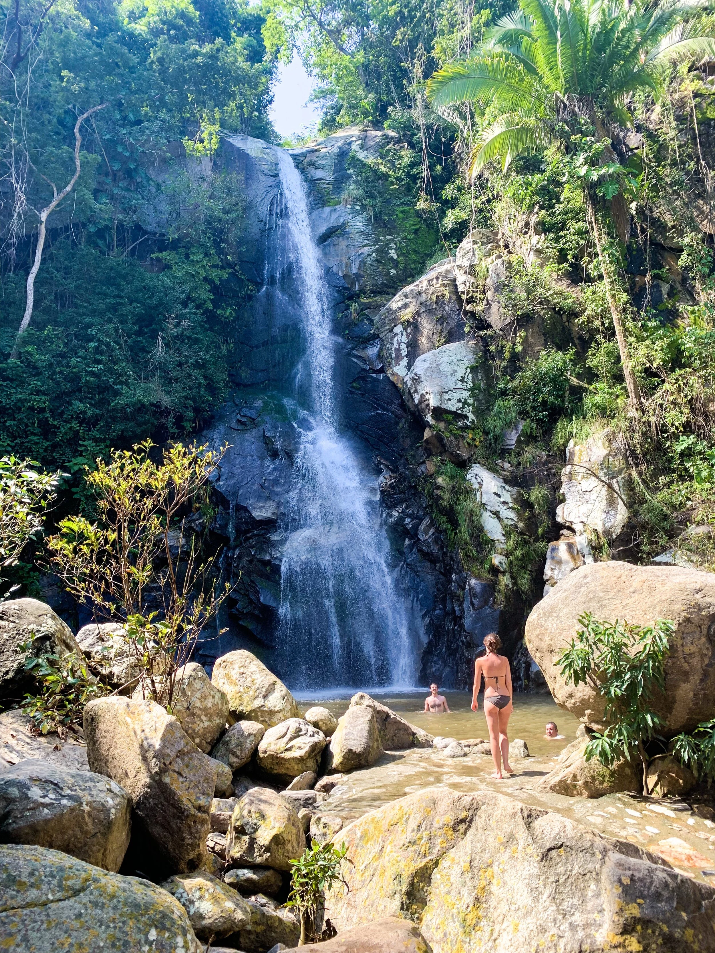 Guest walking toward Yelapa waterfall while friends swim on a boutique My Deztination tour.