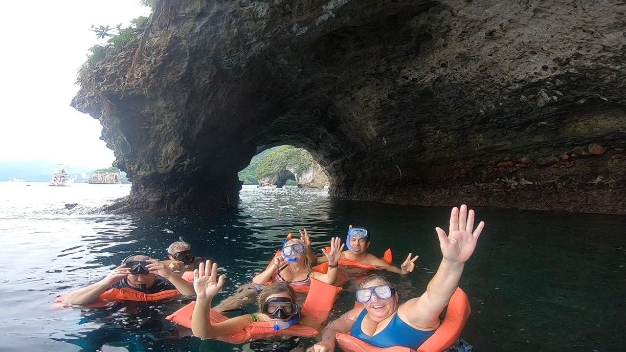 Group with masks and buoyancy aids raising hands on My Deztination snorkel tour.
