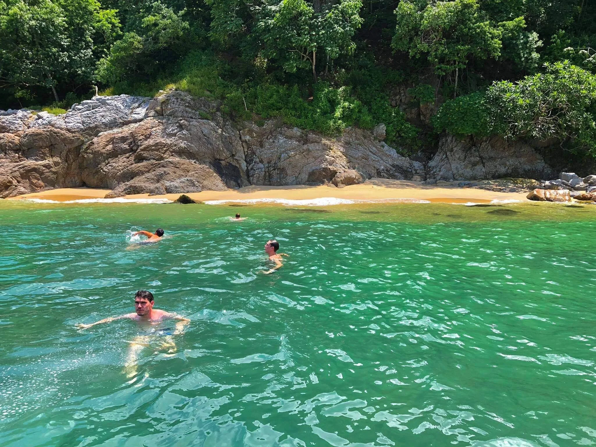Four guests swimming toward secluded private beach on Los Arcos excursion.