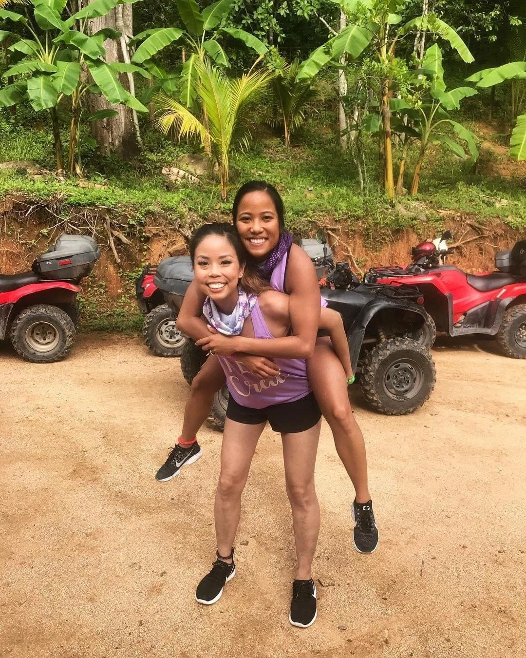 Two girls posing and laughing in front of ATVs on My Deztination tour.