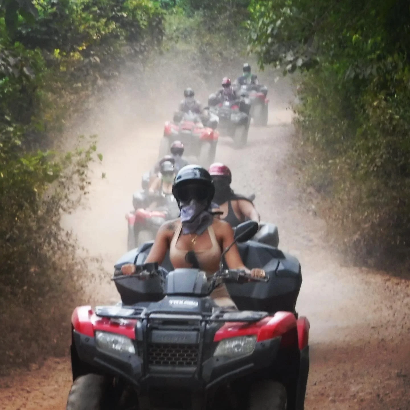ATVs driving toward camera on dirt road with My Deztination guides.