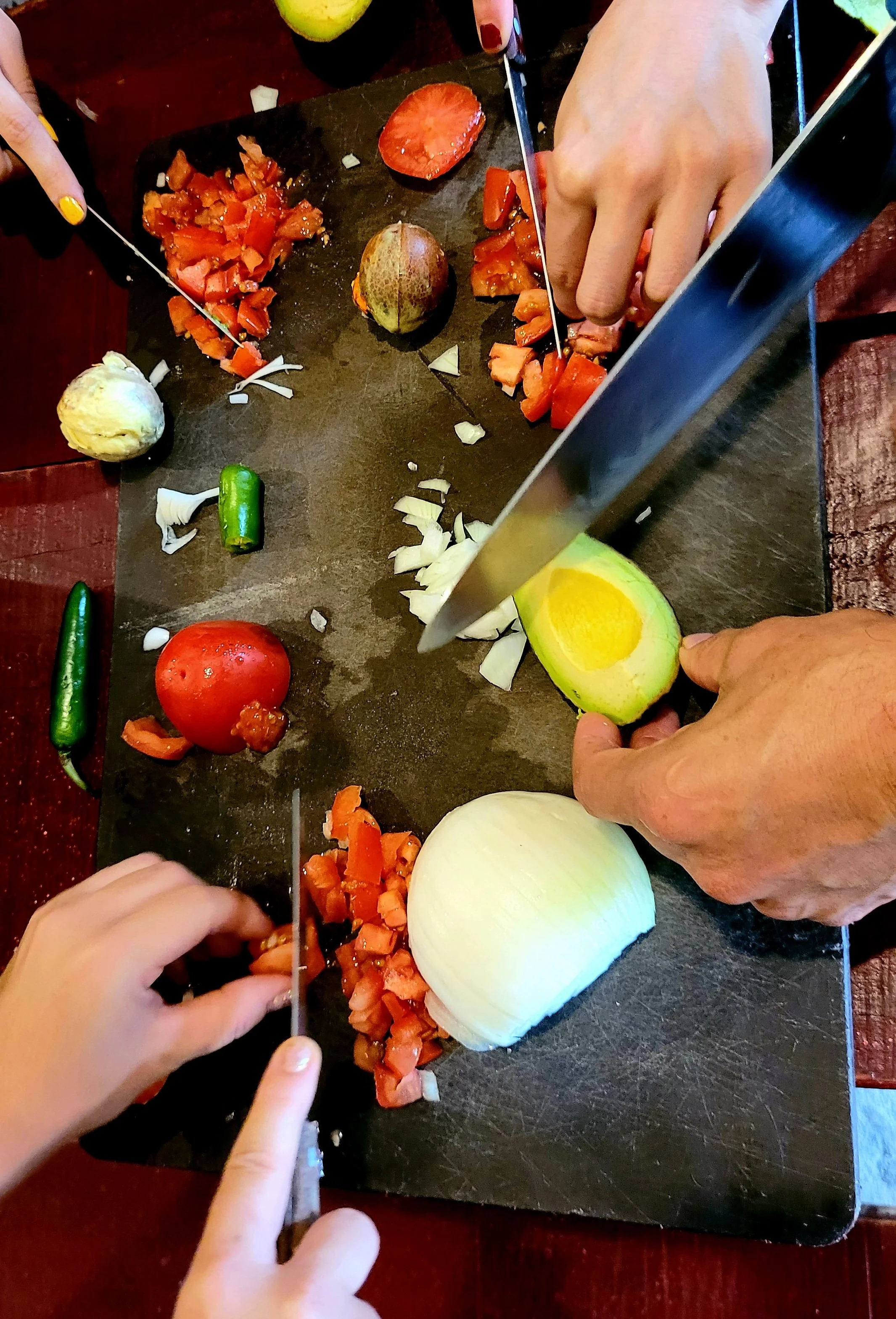 Overhead view of guests chopping tomato, avocado, and onion on My Deztination tour.