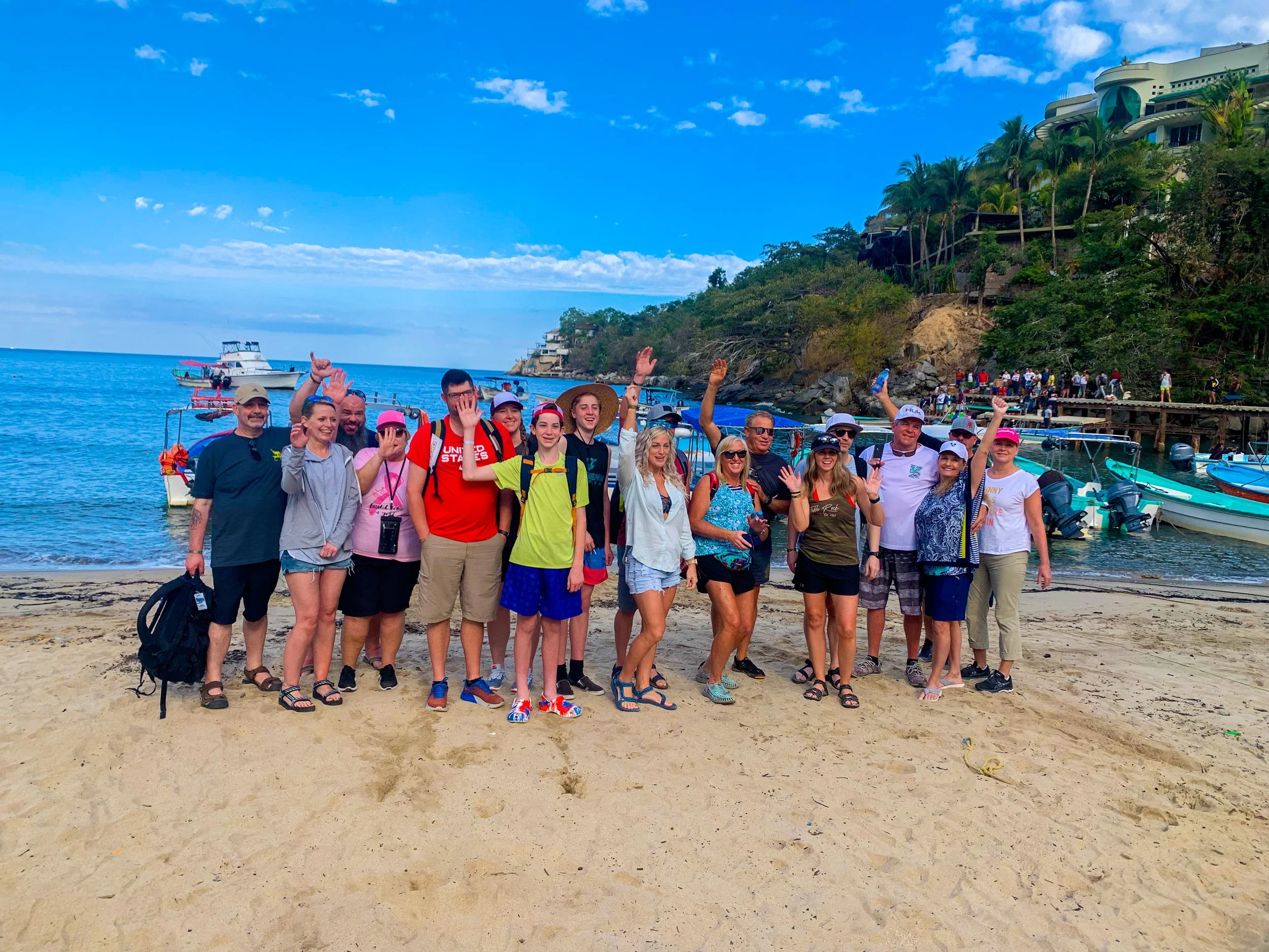 Big group waving happily on beach during My Deztination snorkeling tour.
