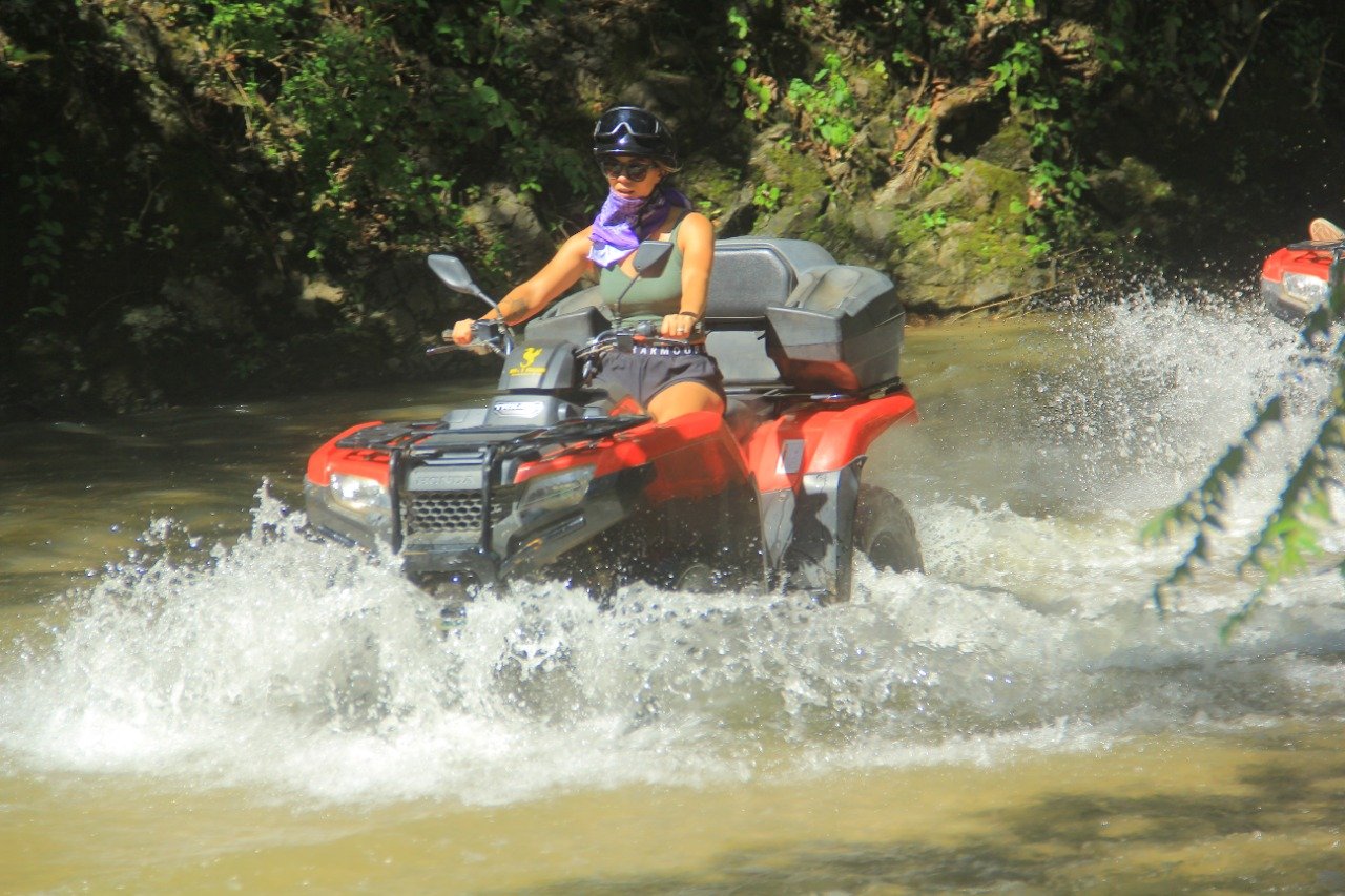 Guest riding ATV through water crossing with My Deztination.
