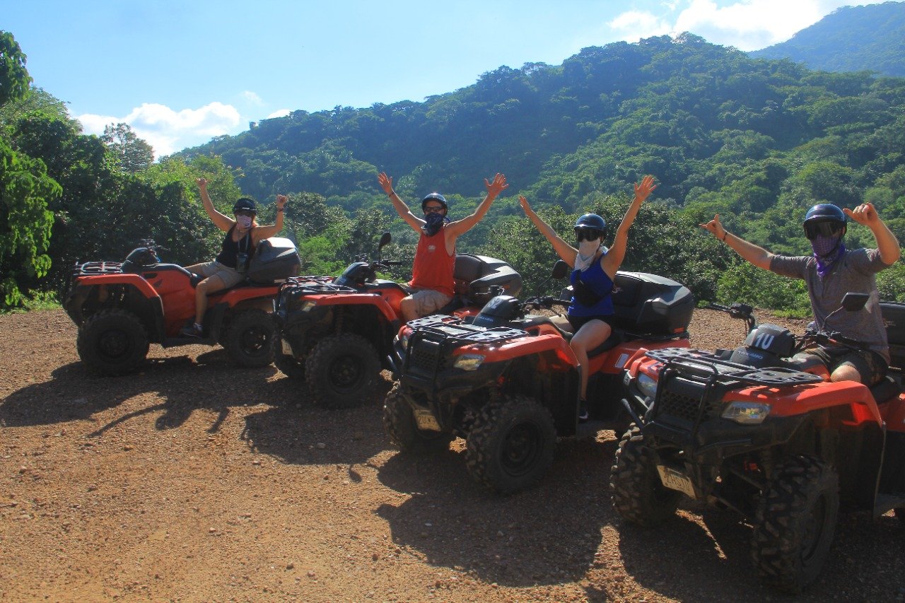 Four friends on ATVs raising hands with mountains, My Deztination.