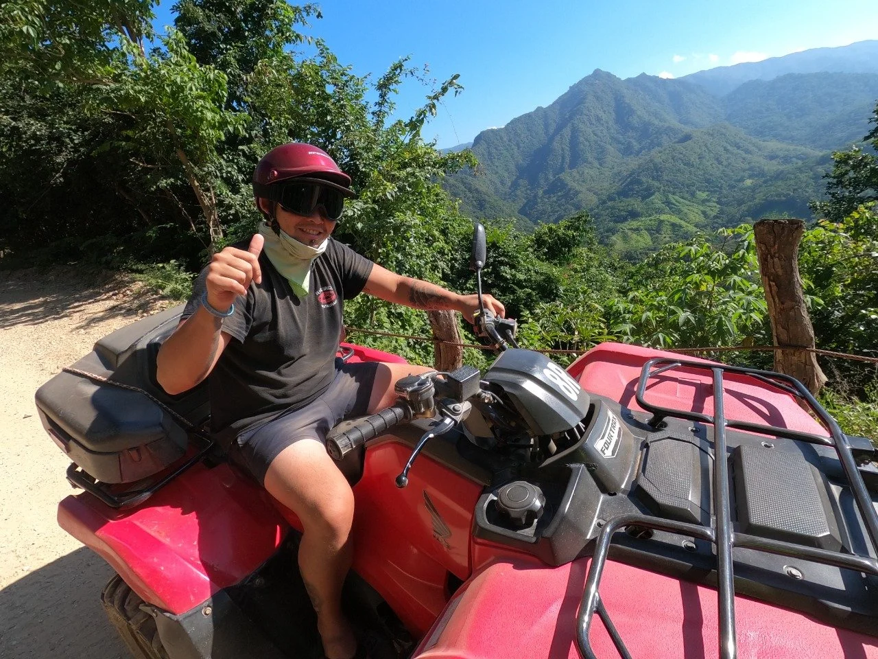 Guest with thumbs up on ATV with mountain backdrop, My Deztination.