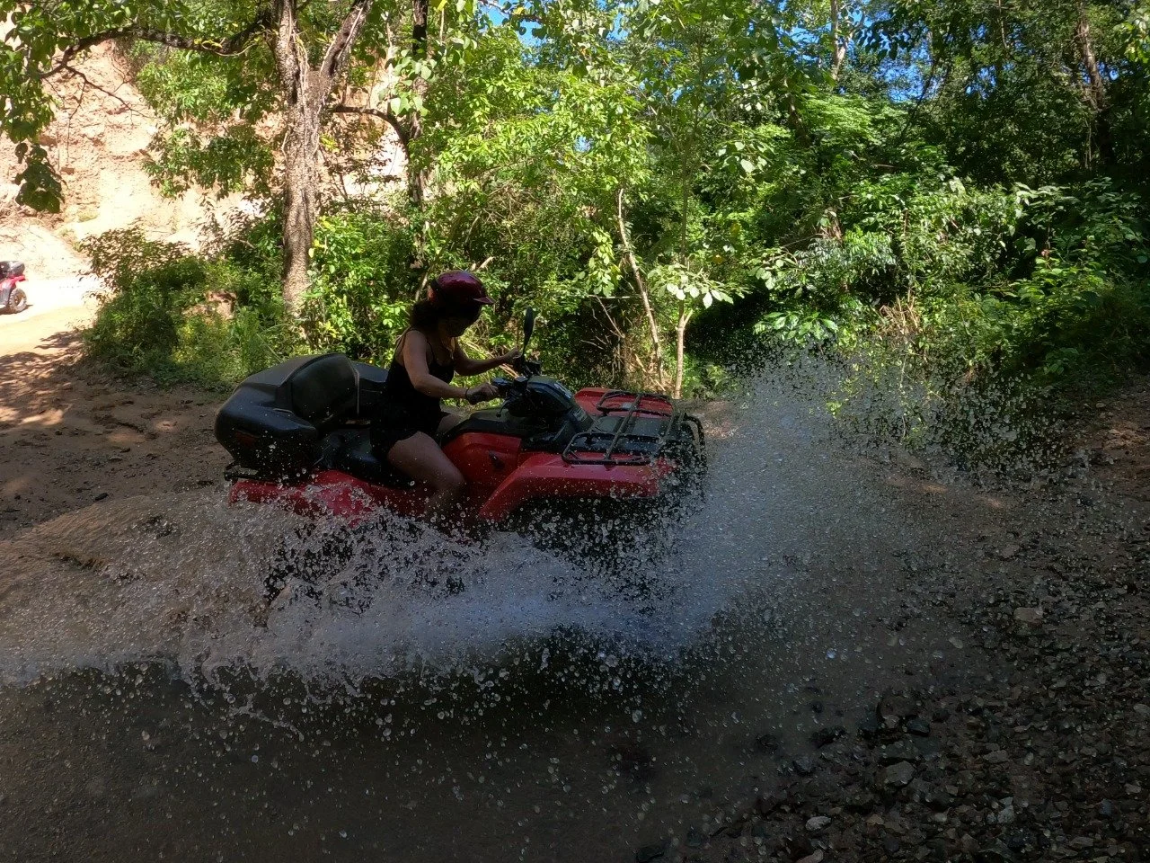 Guest riding ATV through shallow water on My Deztination tour.