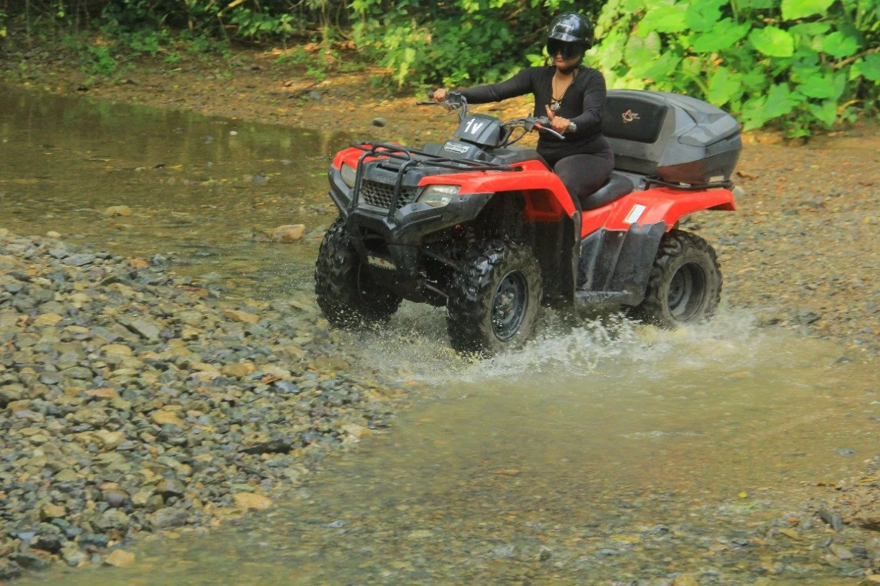 Guest driving ATV through river crossing with My Deztination.
