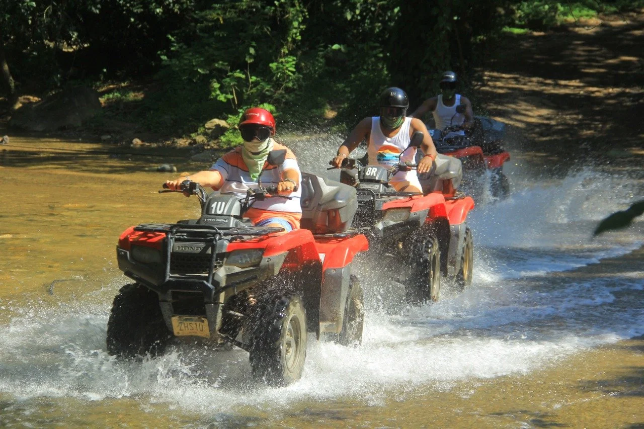 Three riders on ATVs splashing through water with My Deztination.