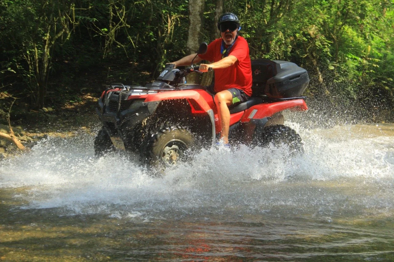 Guest laughing with mouth open splashing water on ATV, My Deztination.