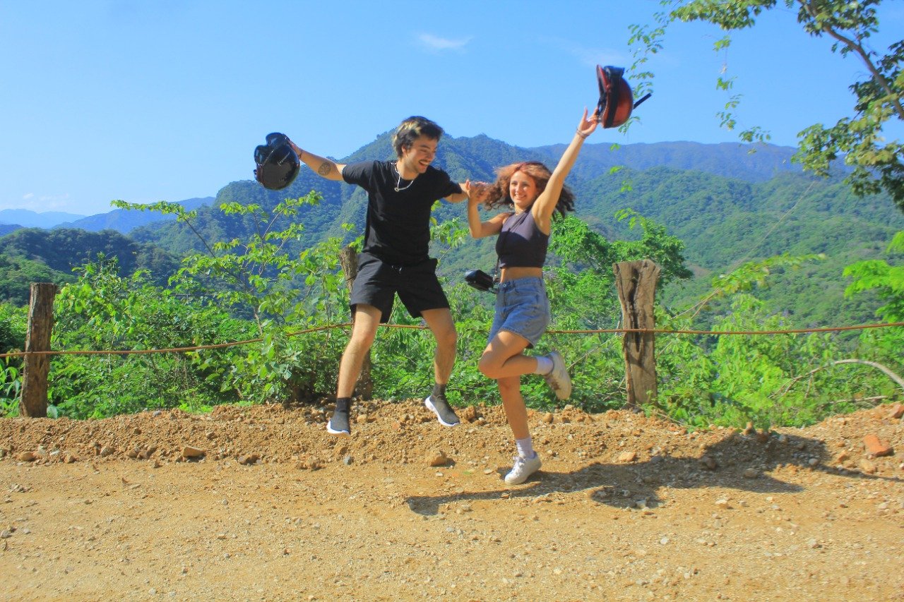 Couple jumping in air celebrating with mountains, My Deztination tour.