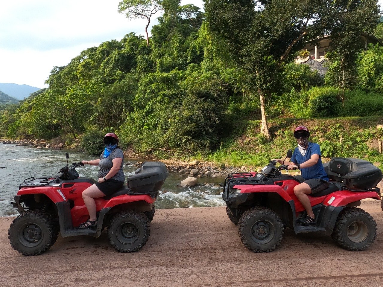 Two riders on ATVs posing by river during My Deztination tour.