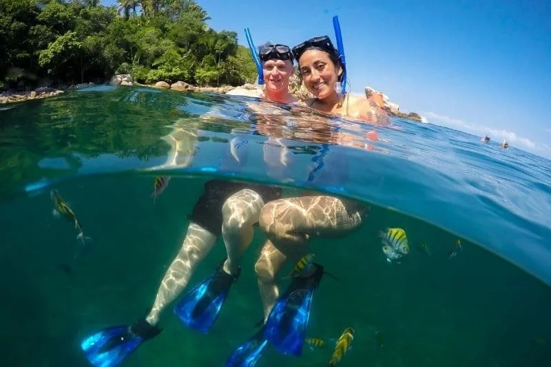 Couple snorkeling smiling together, half above half below water view, My Deztination.