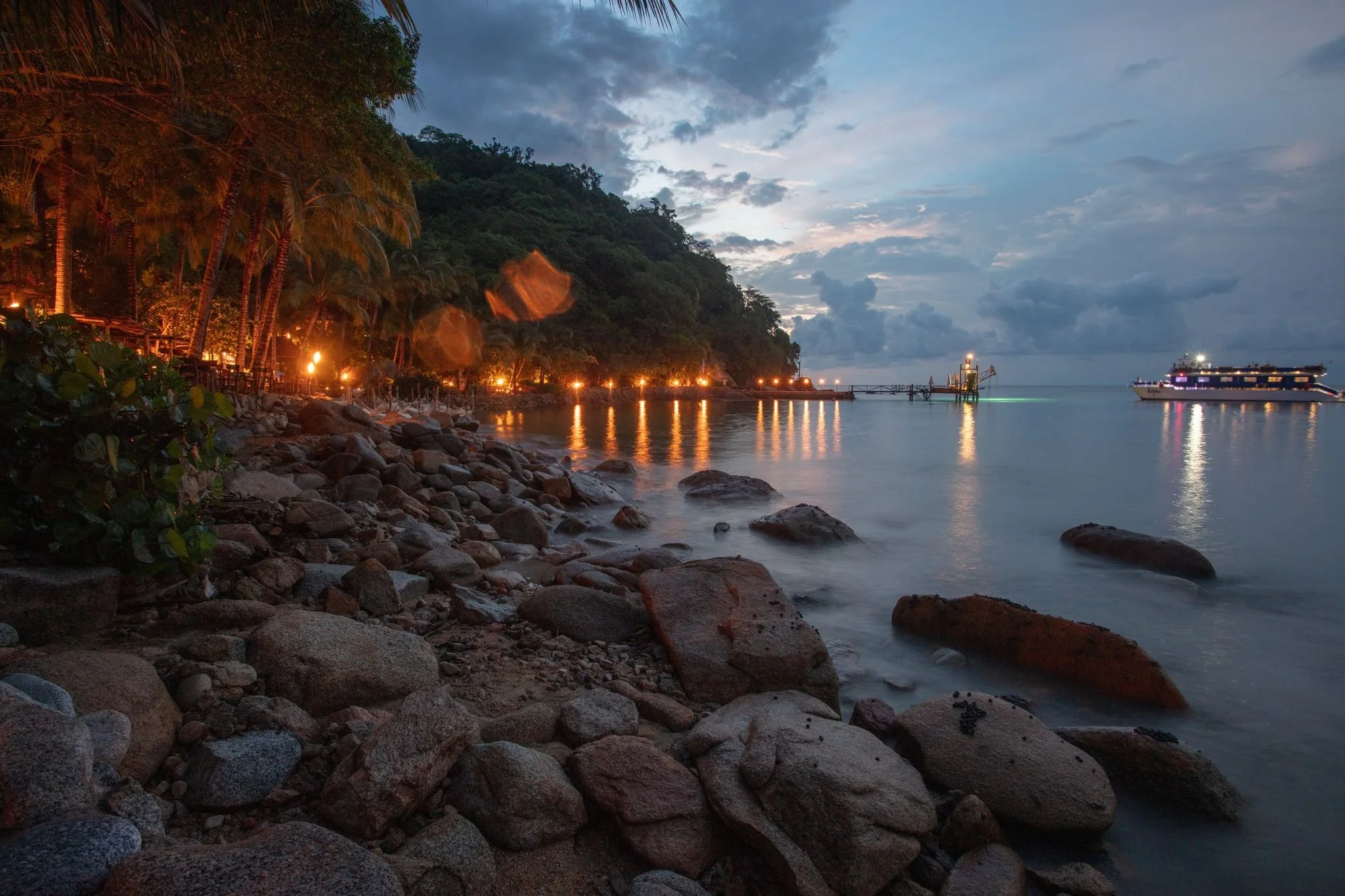 Warm candlelit lights glowing across beachfront on My Deztination evening tour.