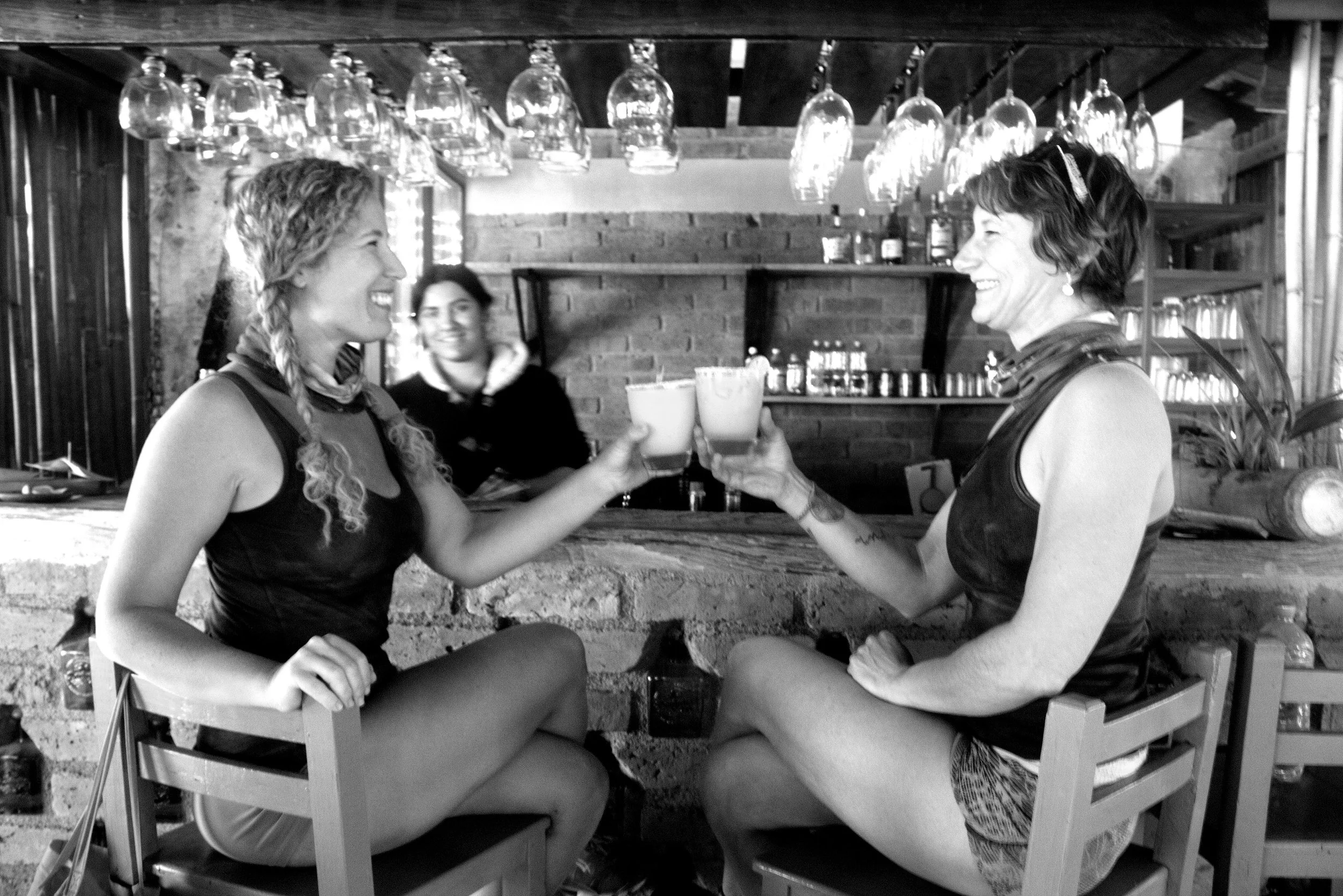 Two girls cheering with drinks at bar after My Deztination adventure.