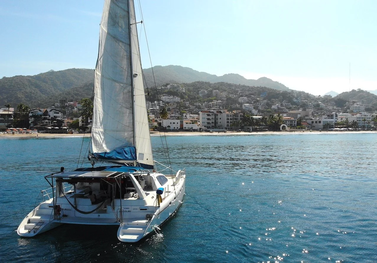 Catamaran floating with mountains and Puerto Vallarta behind, My Deztination.