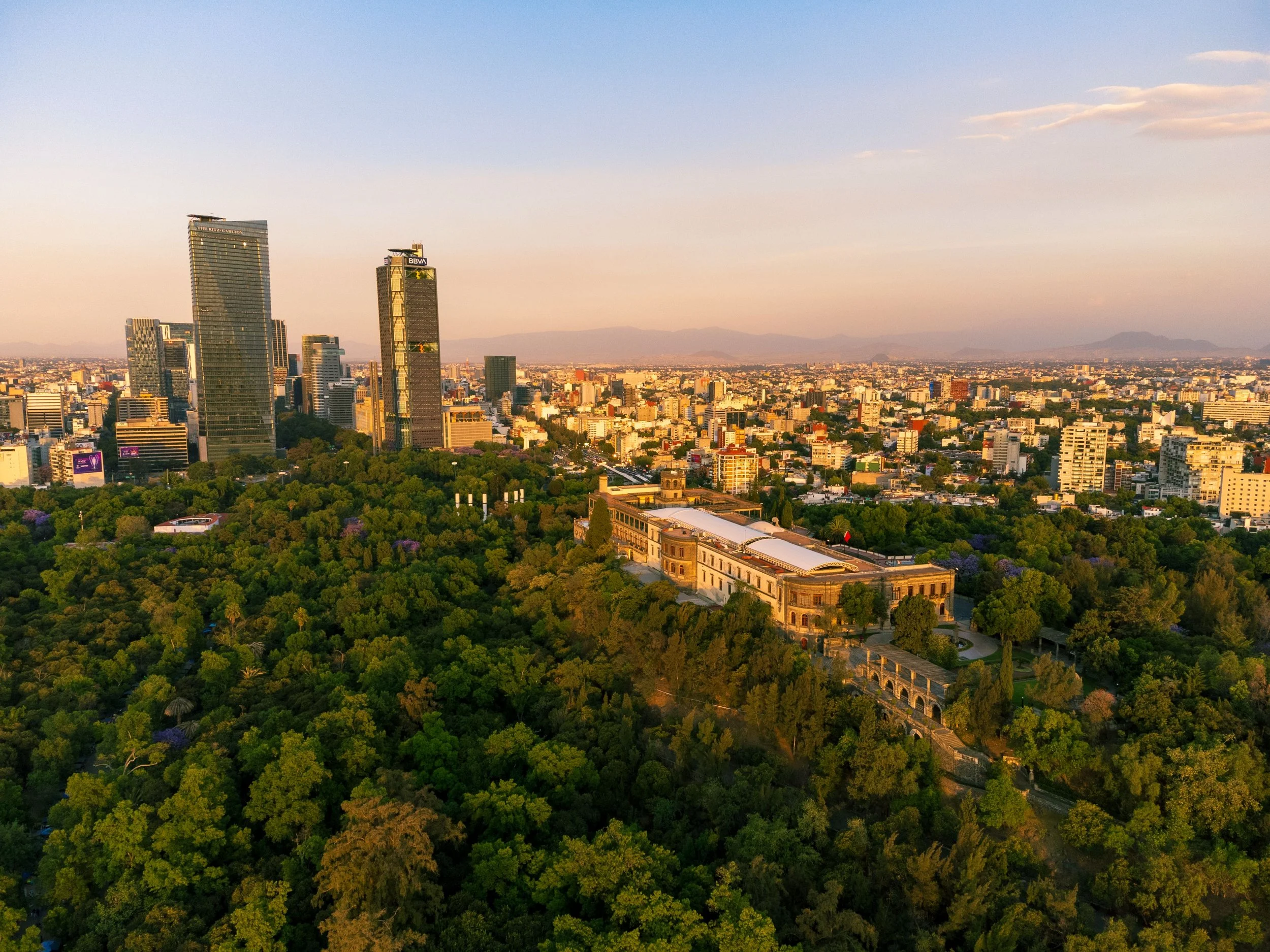 Breathtaking aerial view of Chapultepec Castle amidst lush greenery against the Mexico City skyline at sunset - Mexico City is a green city with many parks in each neighborhood
