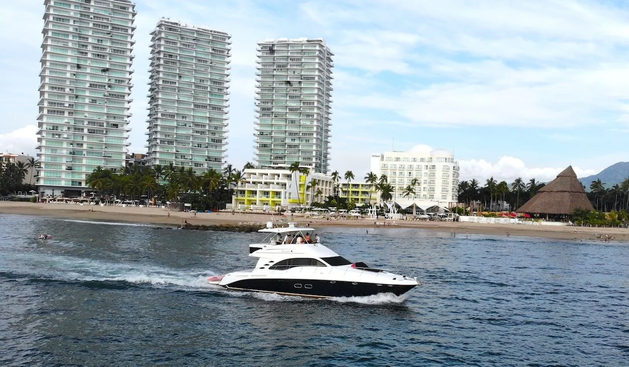 Luxury yacht sailing with beach and hotels behind on My Deztination bay cruise.