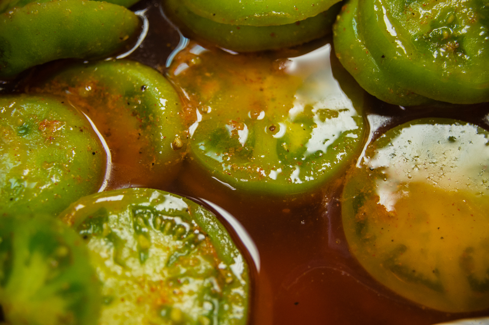 Green tomatoes marinating for battering and frying.
