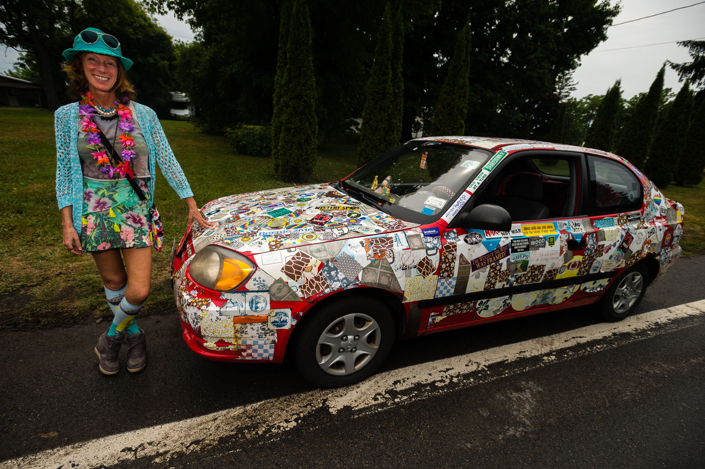 Jesse Klein, a resident of Auburn, stands next to her third vehicle owned and adorned with a myriad of stickers during the annual "50 Mile Yard Sale", Saturday, July 20, 2016 along Route 90 in the Cayuga Lake region of the Finger Lakes, New York. Klein travels to the annual event which she refers to as her "yearly weekend vacation" as an opportunity to shop for objects and materials to repurpose into functional art.
