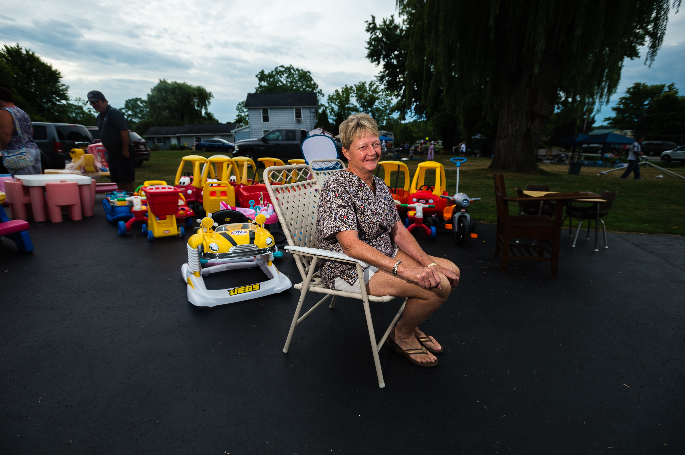 Village of Cayuga resident Sandy Ehrlich sits in her driveway for a portrait among children's toys during the annual "50 Mile Yard Sale", Saturday, July 20, 2016 along Route 90 in the Cayuga Lake region of the Finger Lakes, New York.