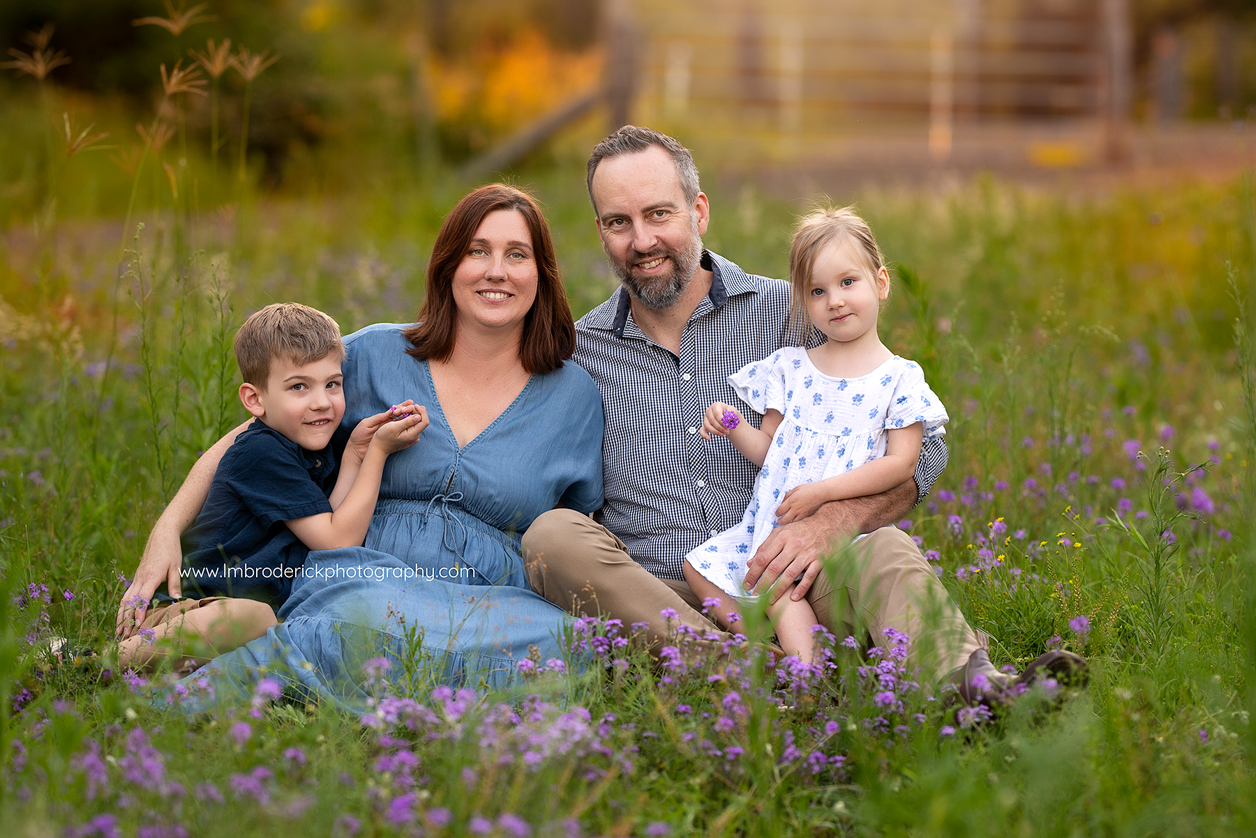 Fernvale Family sitting in grass with purple flowers along the Brisbane Valley Rail Trail