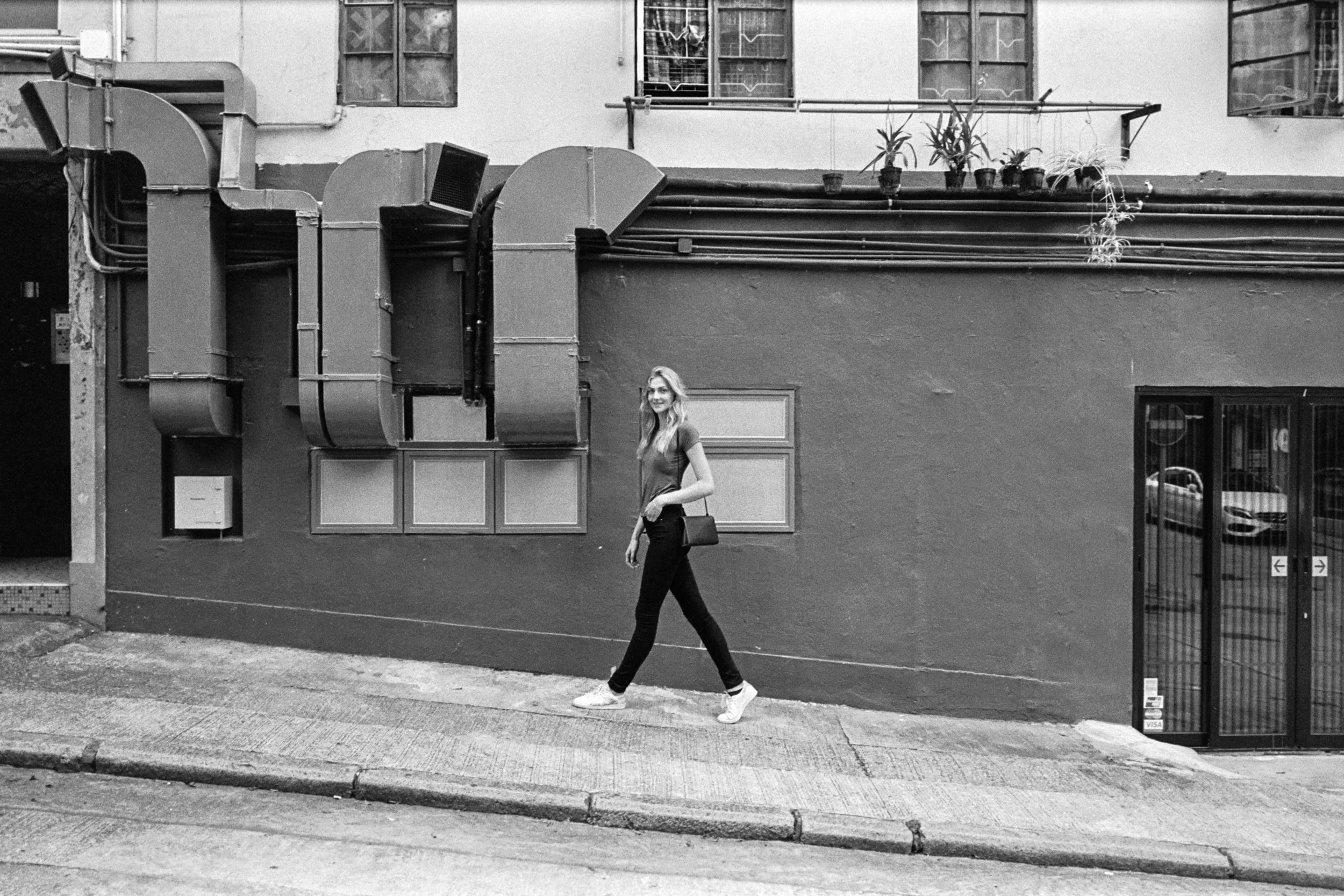 Kodak Tri-X 400 @ 28mm Focal Length - Walking uphill. Compositional variables include wall texture, HVAC vents, and windows.