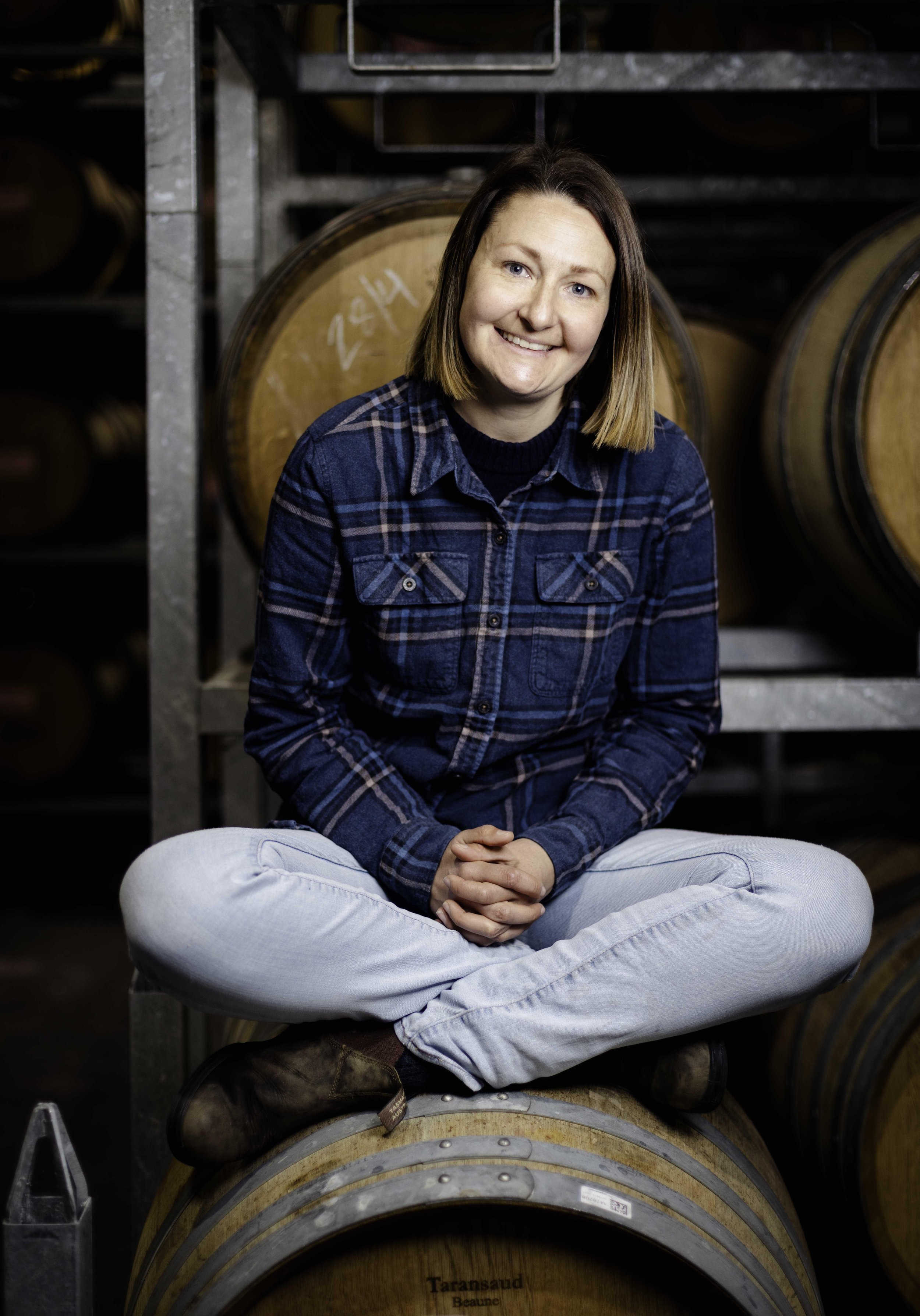 Winemaker Alice Davidson sitting on a wine barrel