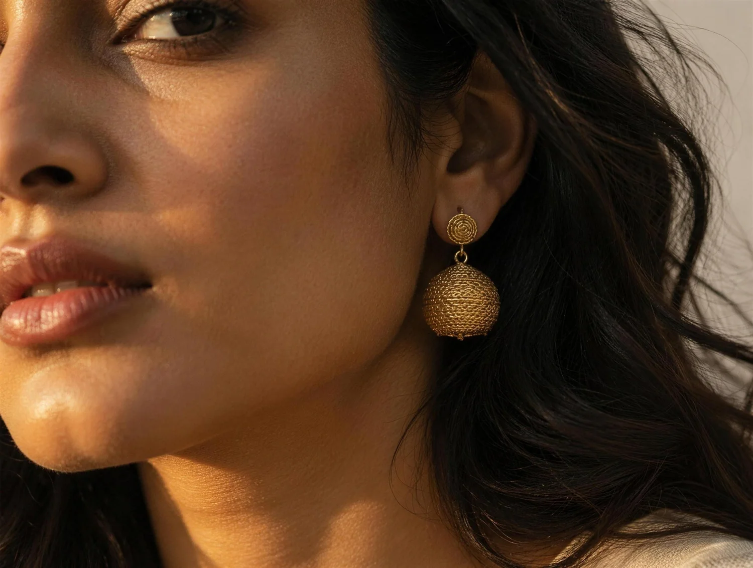 Woman wearing a handcrafted gold earring, brand identity design for Antara Jewellery by Yellow Fishes, a branding agency in Mumbai