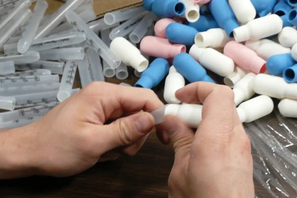 close up of a person placing a dropper bulb onto a medical dropper tube