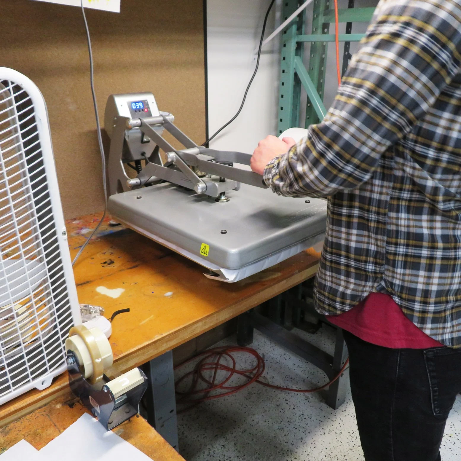 person at heat press machine in production area