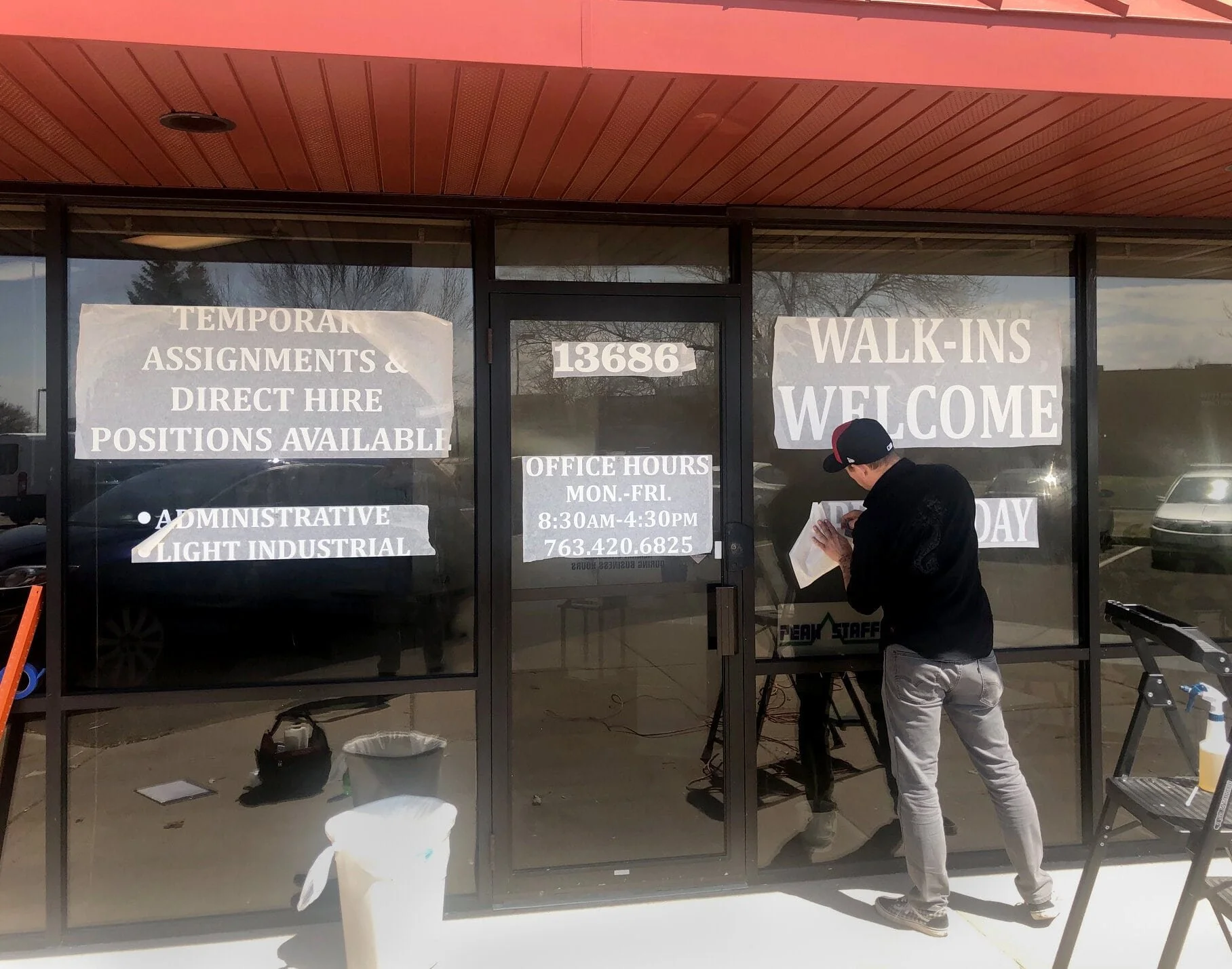 man installing white vinyl on a store front window