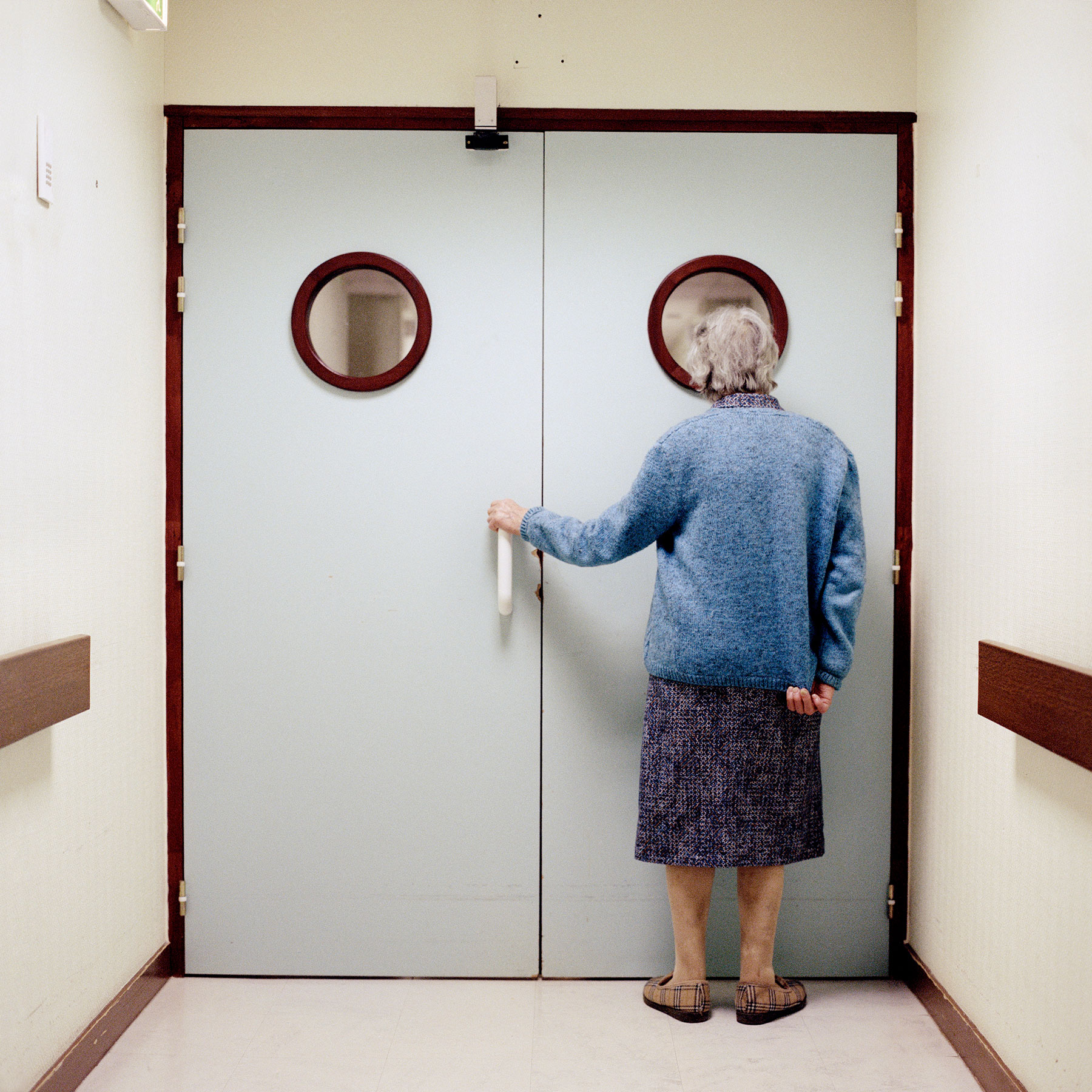  Resident stands in front of the ward’s locked exit. Doors and blocked passing’s are disturbing elements to a person suffering from Alzheimer’s due to the common symptom to regularly often wander about. As a result of the potential risk of getting lo