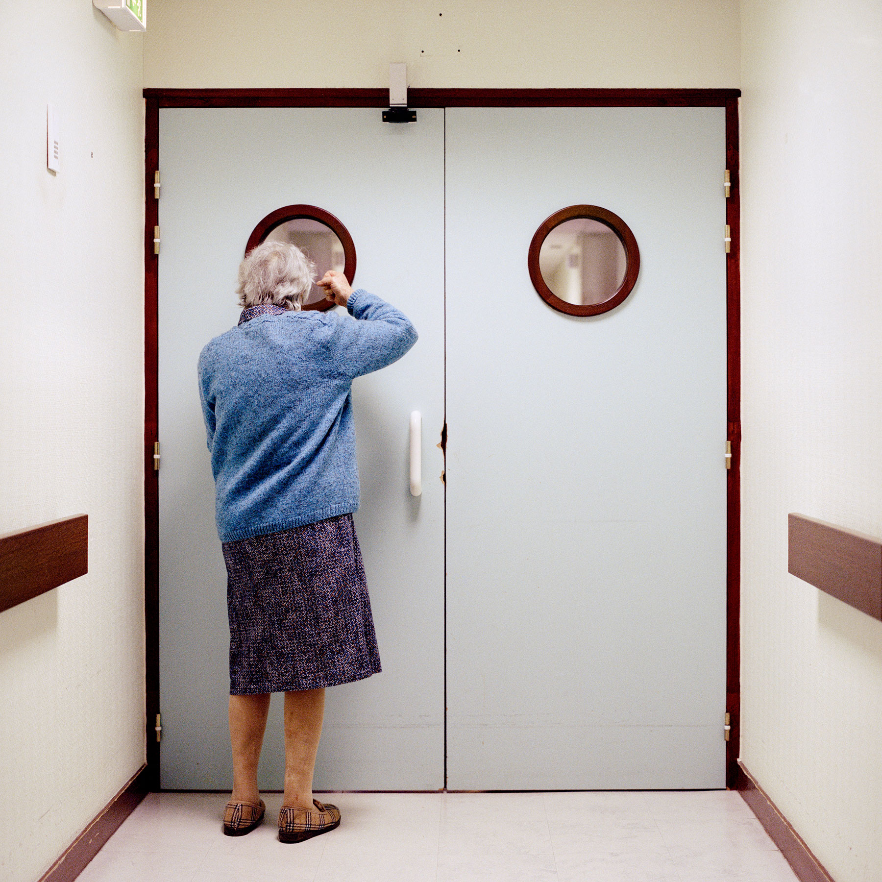  Resident stands in front of the ward’s locked exit. Doors and blocked passing’s are disturbing elements to a person suffering from Alzheimer’s due to the common symptom to regularly often wander about. As a result of the potential risk of getting lo