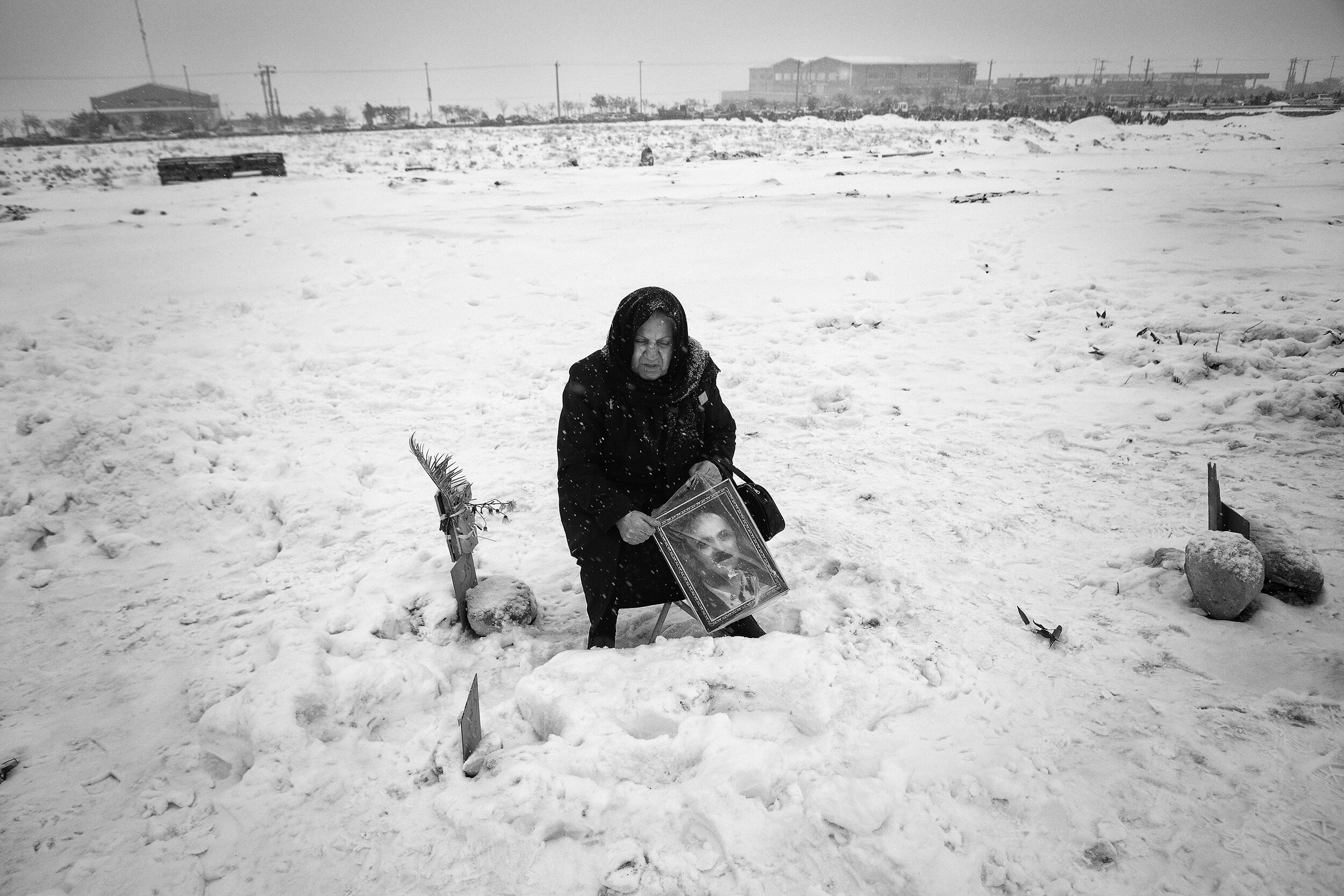  My mother is praying for my father while holding a picture of him in her hands in a cold snowy day.  