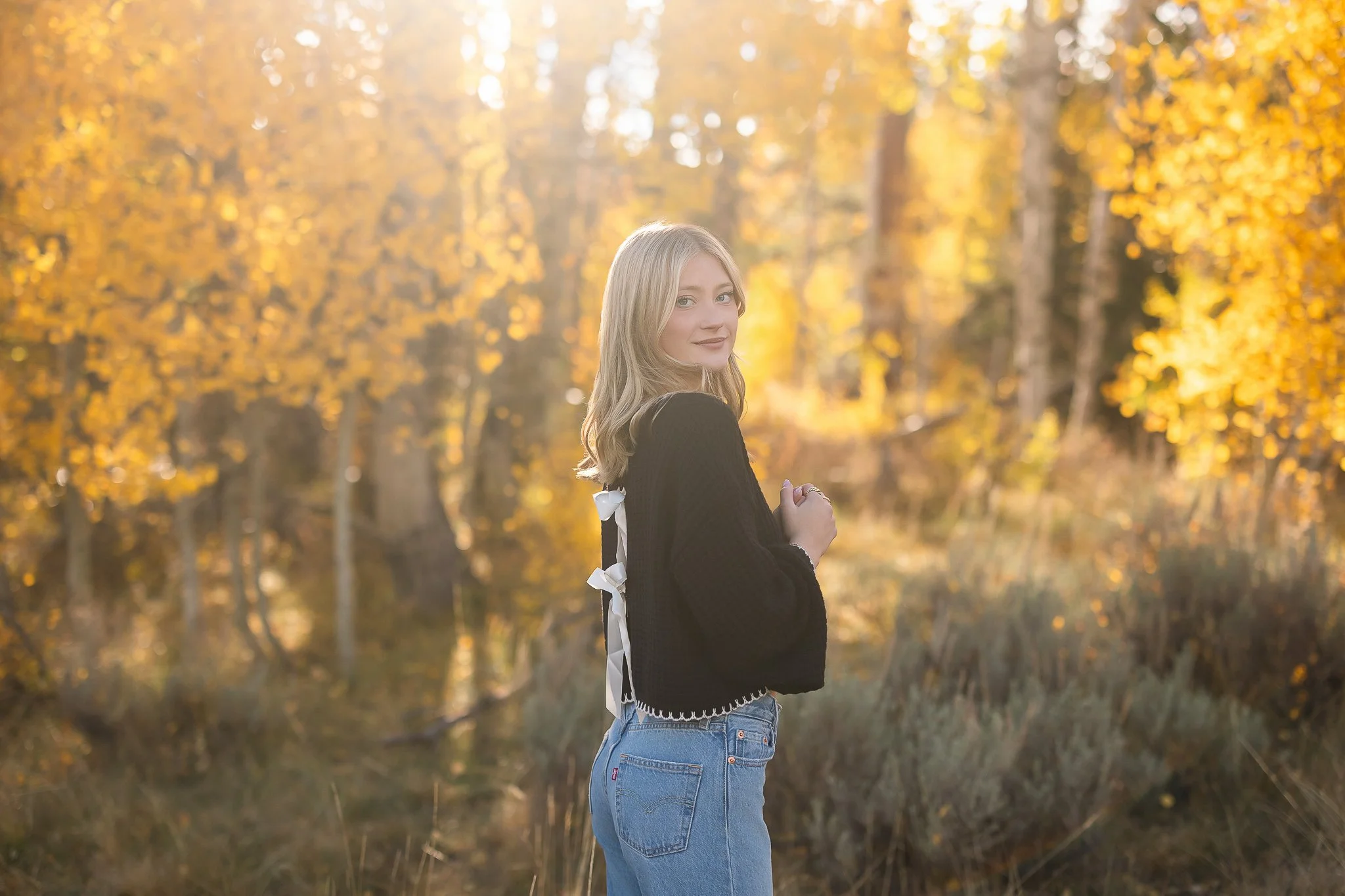 St. Francis High School graduating senior surrounded by golden fall foliage during her senior picture session in Hope Valley, California.