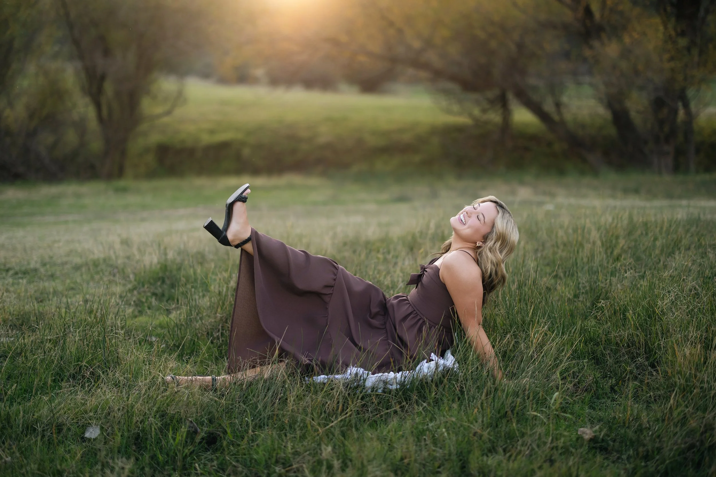 Oak Ridge High School senior laughing in a brown dress during golden hour senior pictures in a grassy field near Folsom Lake, California.
