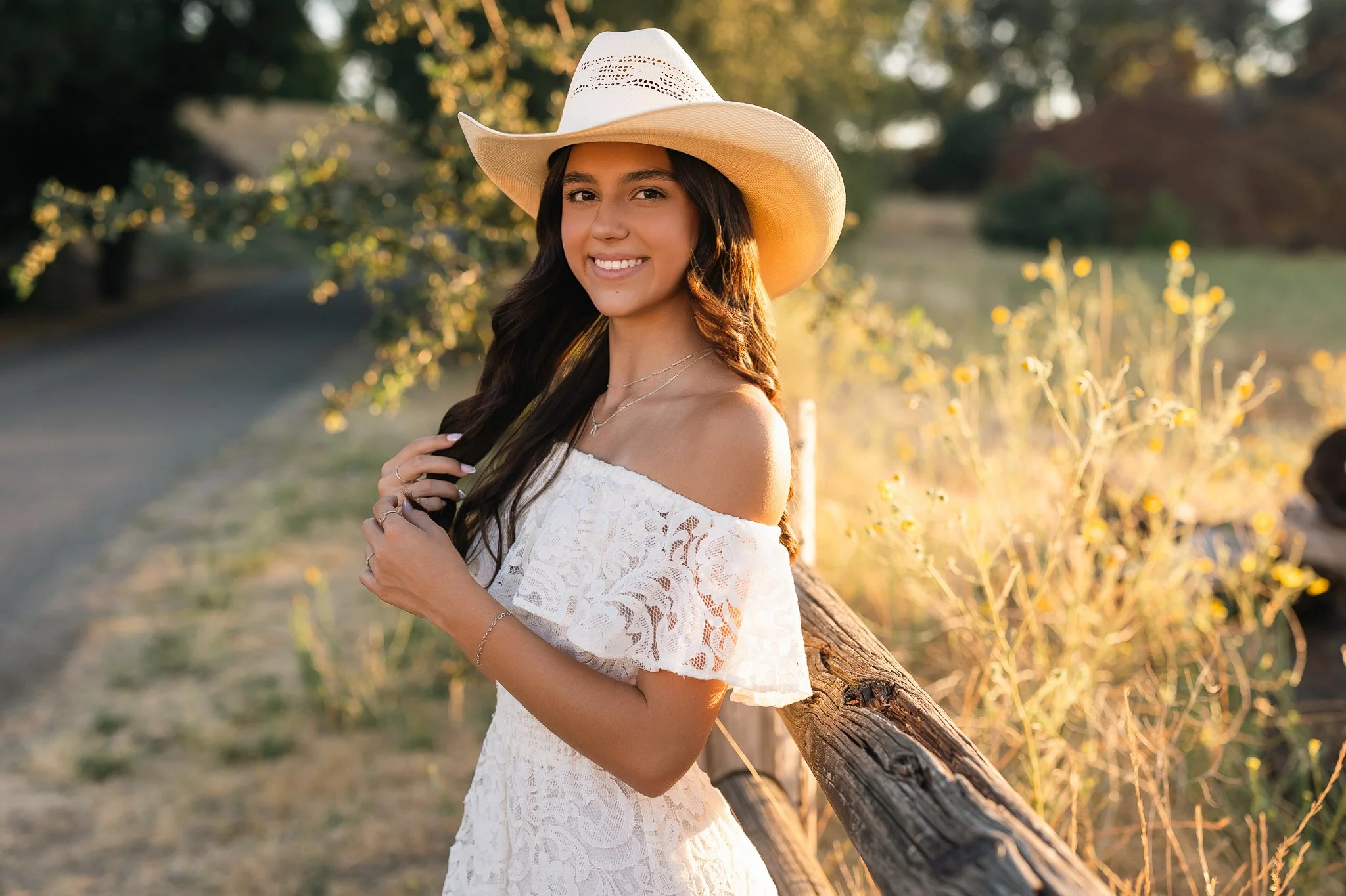 Pleasant Grove High School senior girl wearing a white lace dress and cowboy hat during golden hour senior pictures in Elk Grove, California.