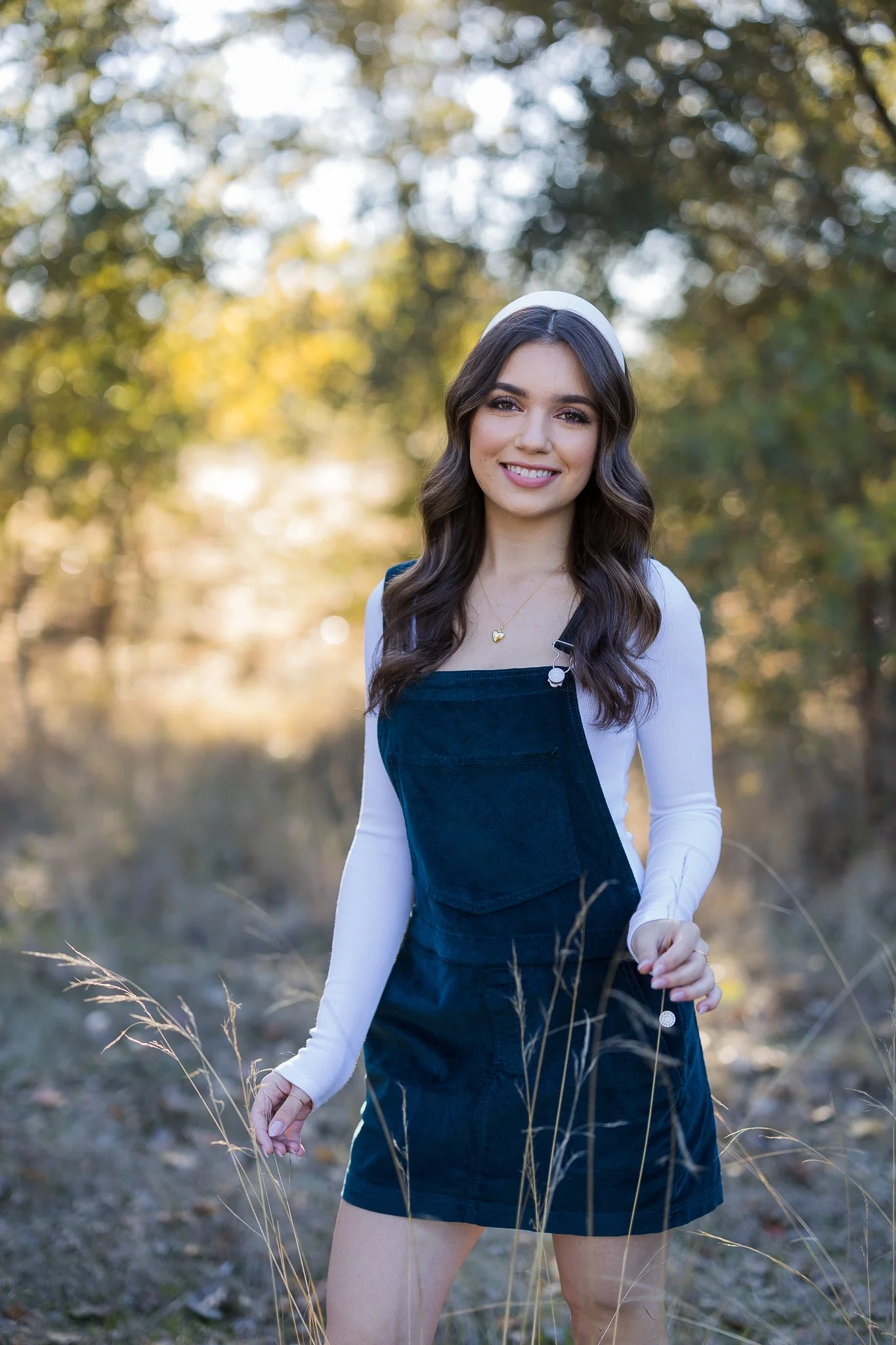 Oakmont High School senior girl posing outdoors among tall grasses during her senior portrait session in Roseville, California.